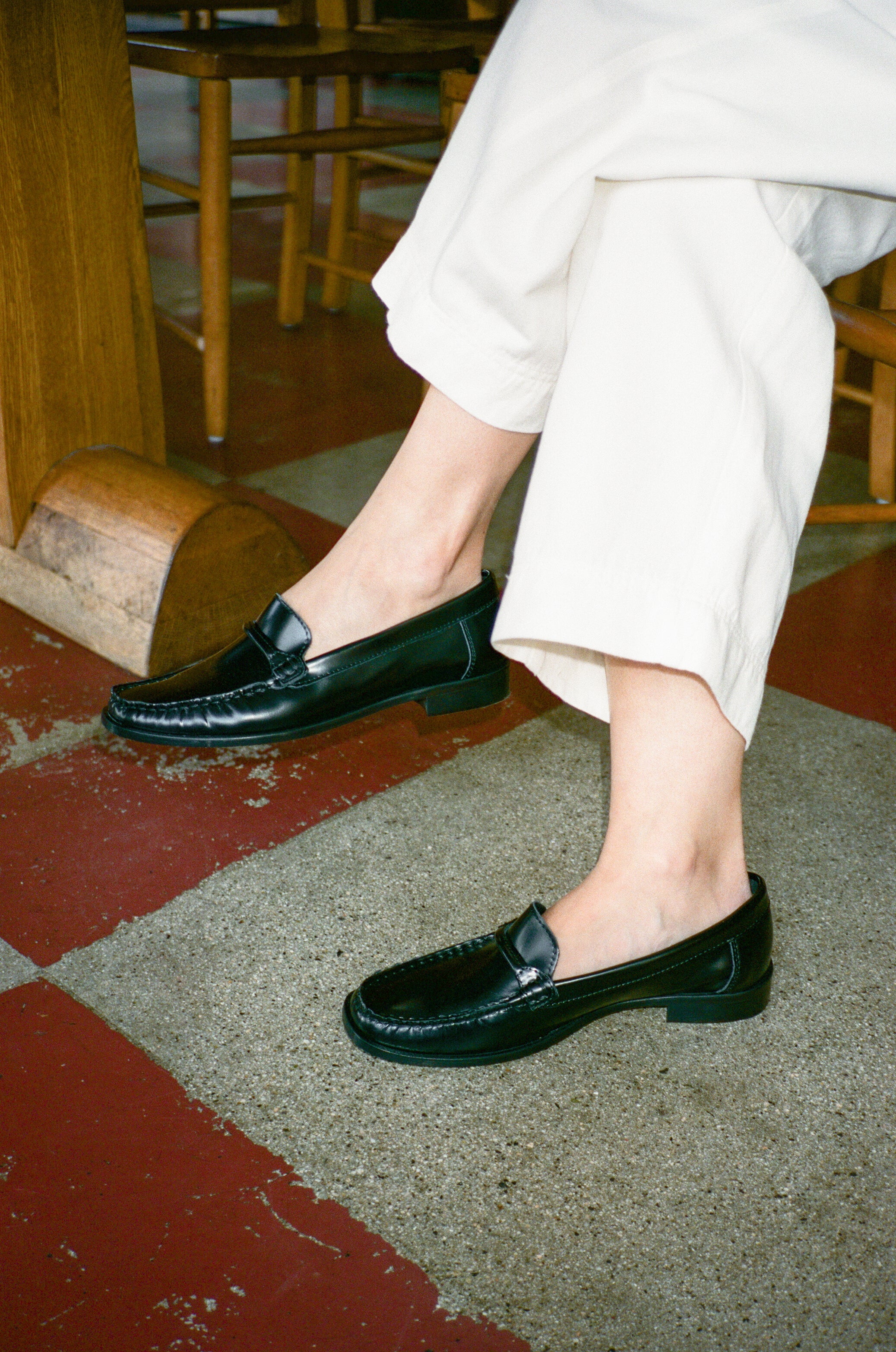 Model wears black leather loafer with tubular strap.
