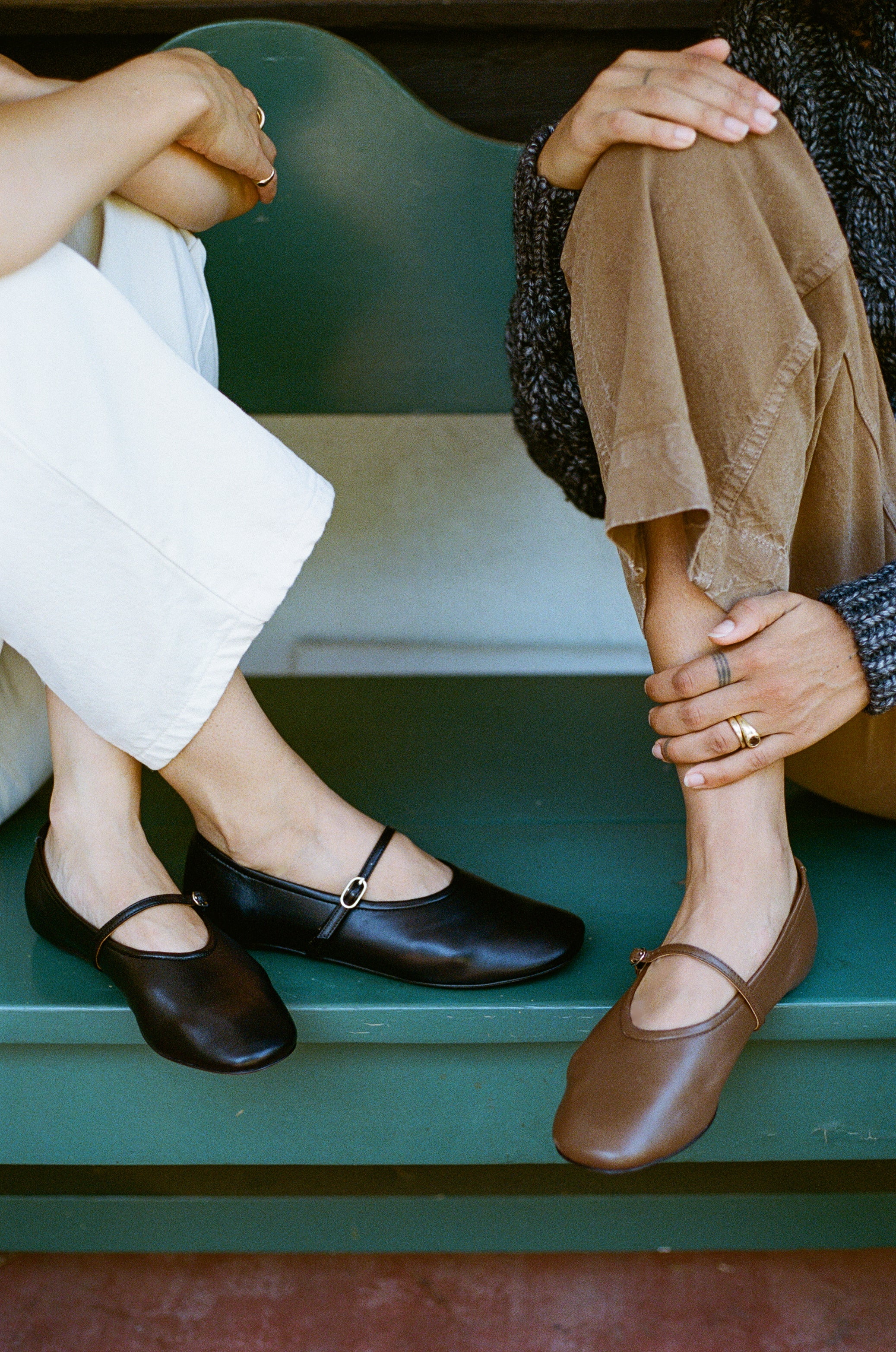 Model wears black leather mary jane style flat shoe with strap and buckle closure.