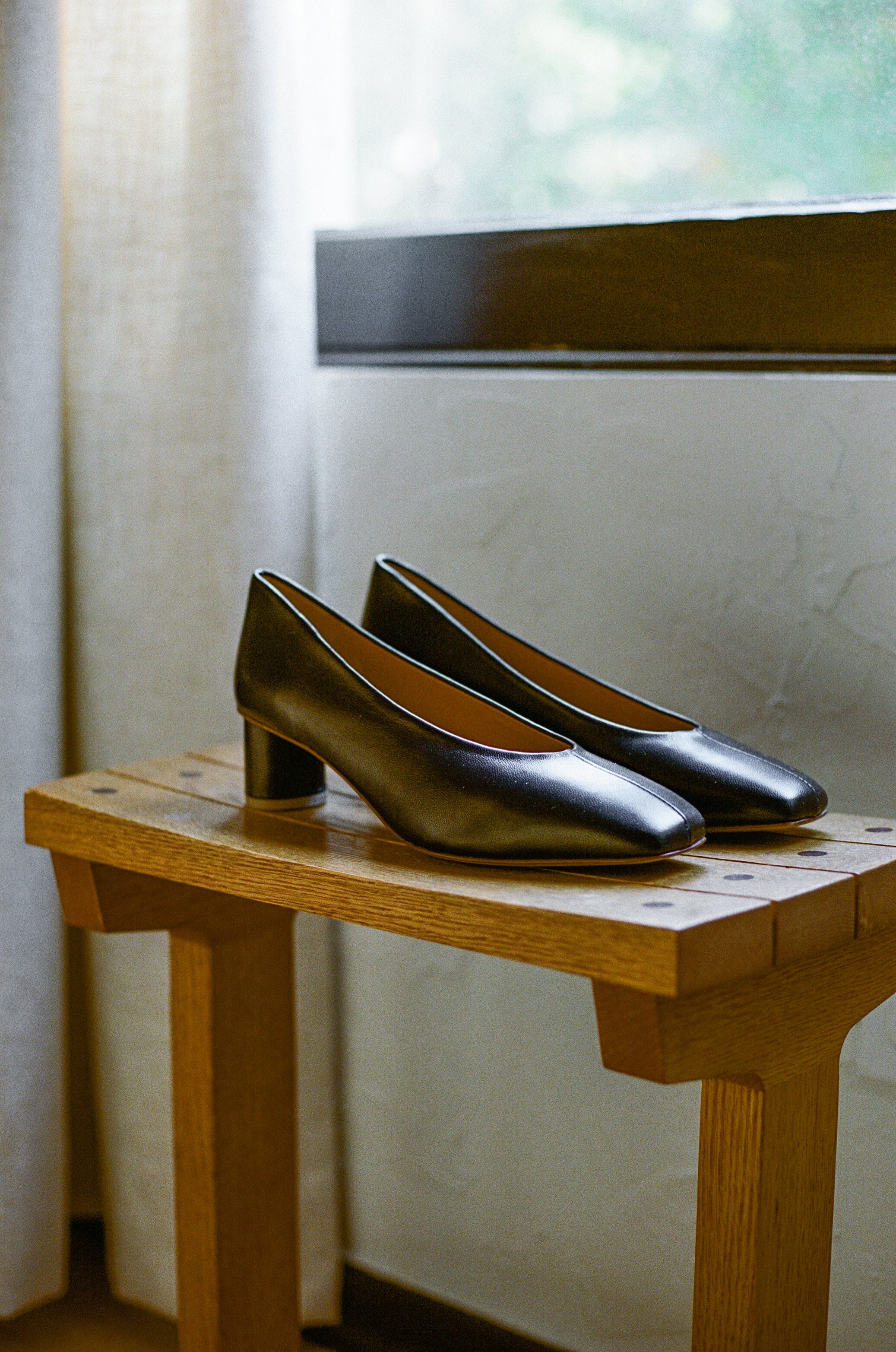 Black leather pumps with sculptural oval heel and center seam.