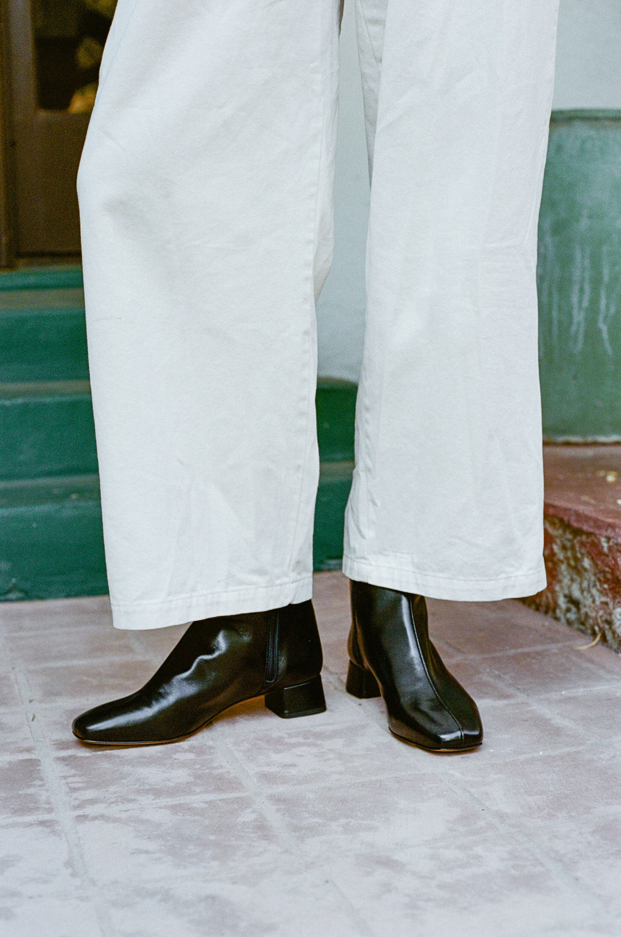 Model wears black ankle boot with center seam and side zipper.