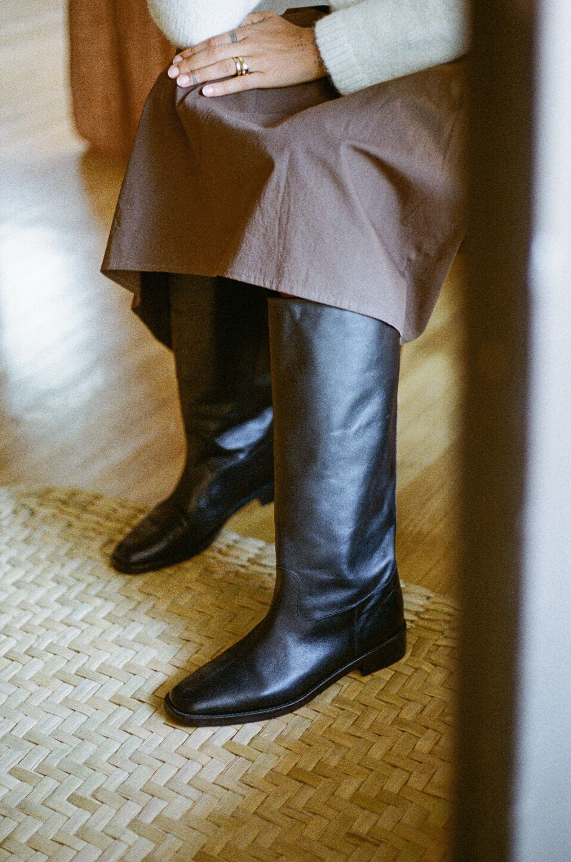 Model wears tall black riding boot with almond shaped toe.
