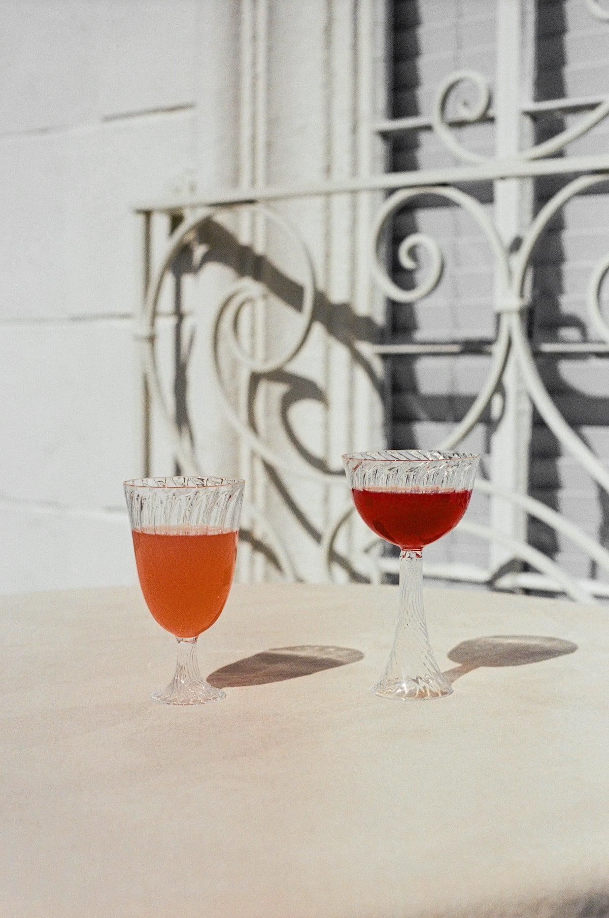 Ribbed wine glass and champagne coupe filled with orange wine.