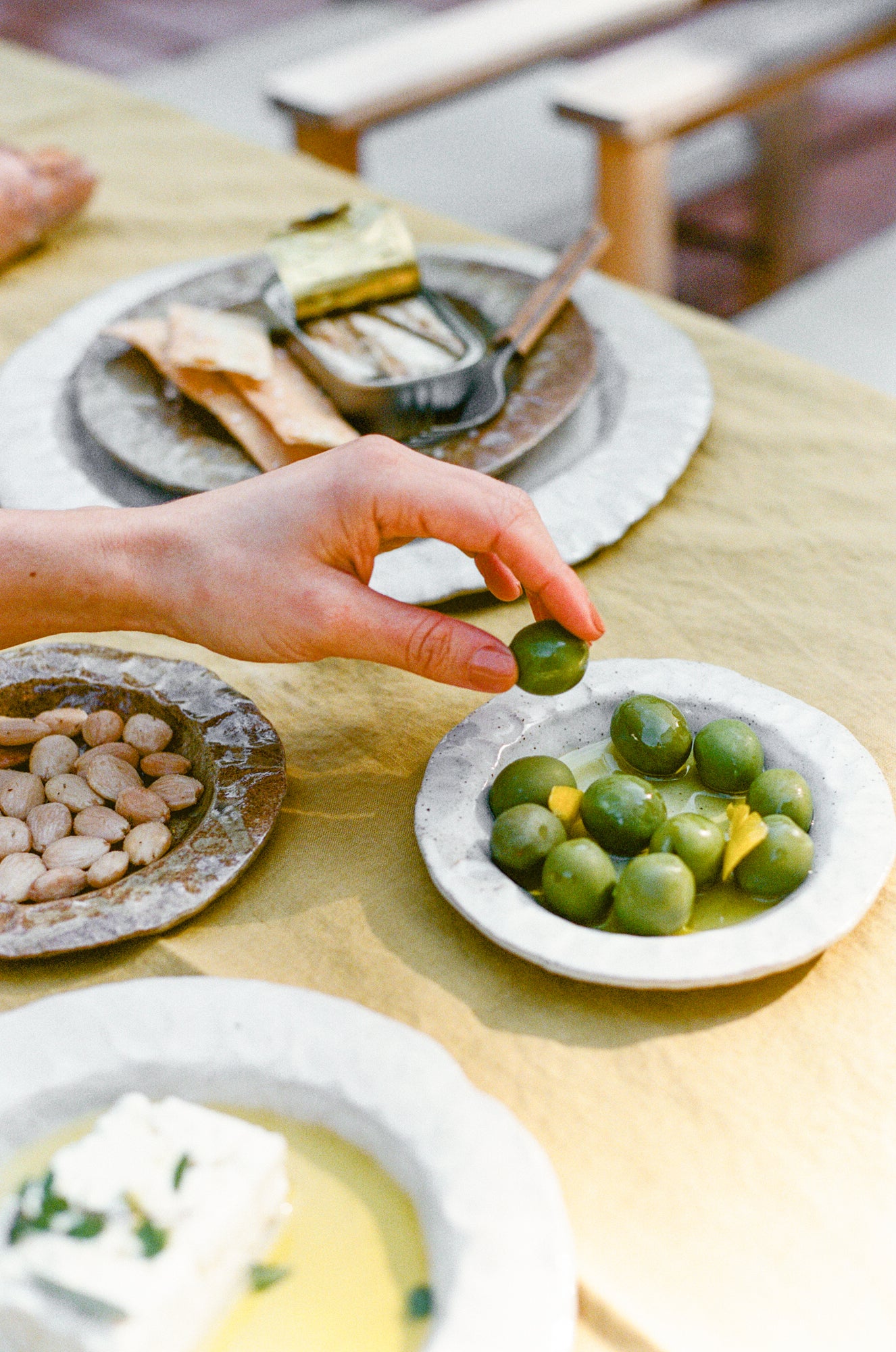 Handmade ceramic plates in varying sizes and colors on table with yellow tablecloth.