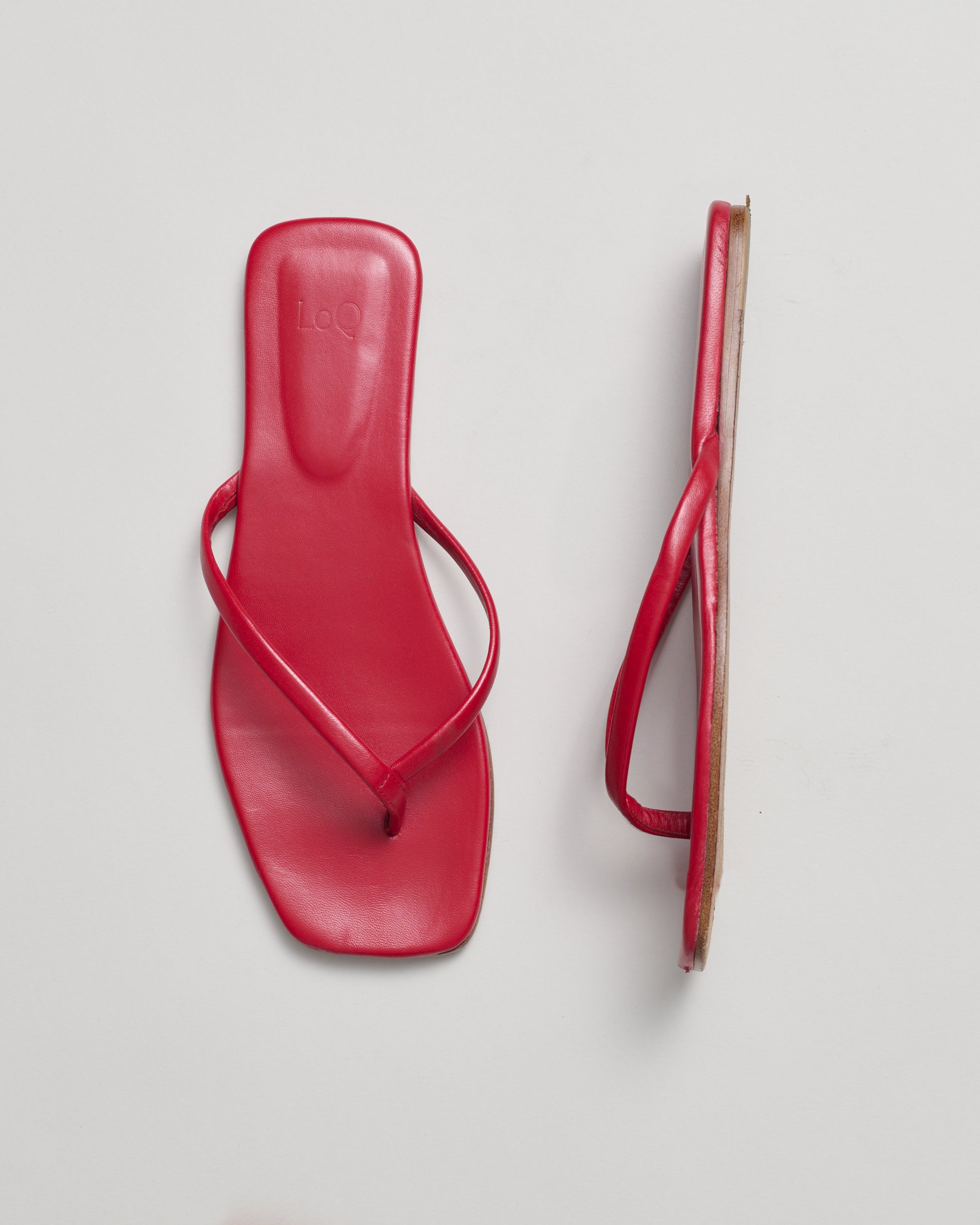 Pair of red minimalist sandals on a gray background