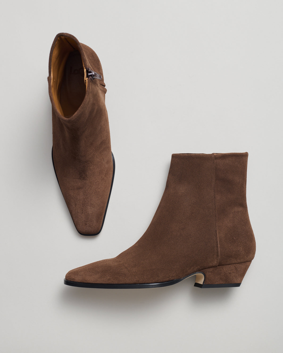 A pair of coffee brown suede leather western style ankle boots with pointed toes and low cuban heel.