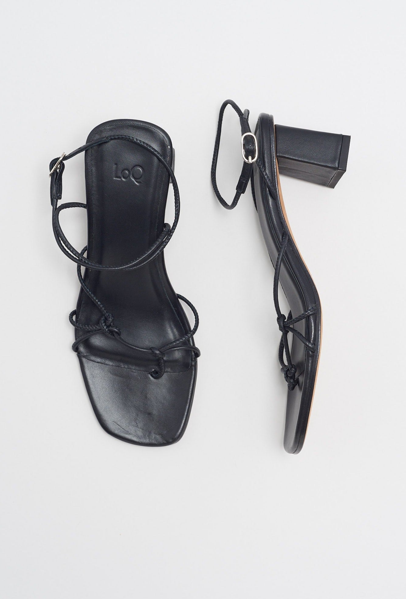 Black high heeled leather sandal with thin knotted straps and ankle wrap buckle closure.