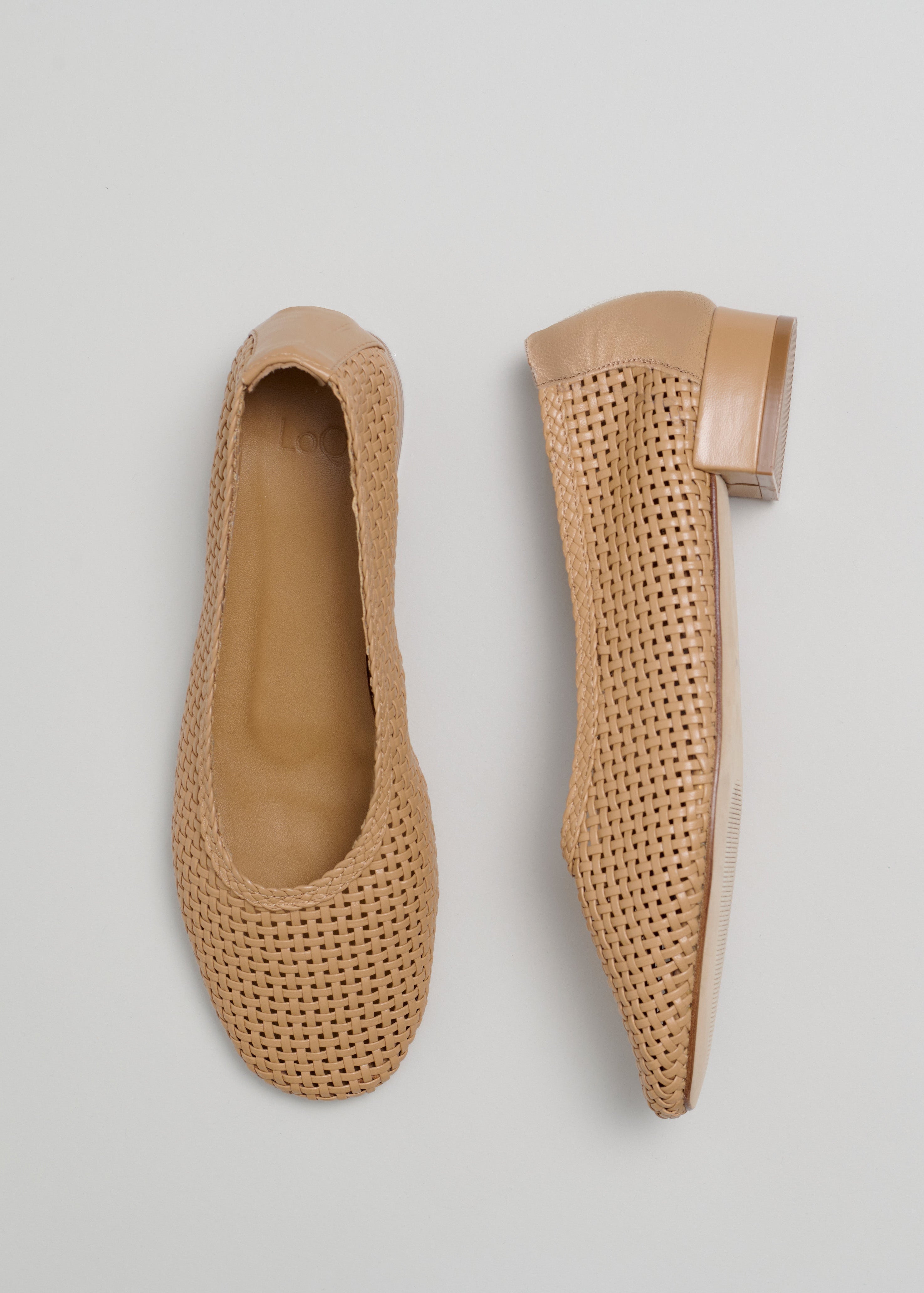 Pair of beige woven shoes on a light gray background