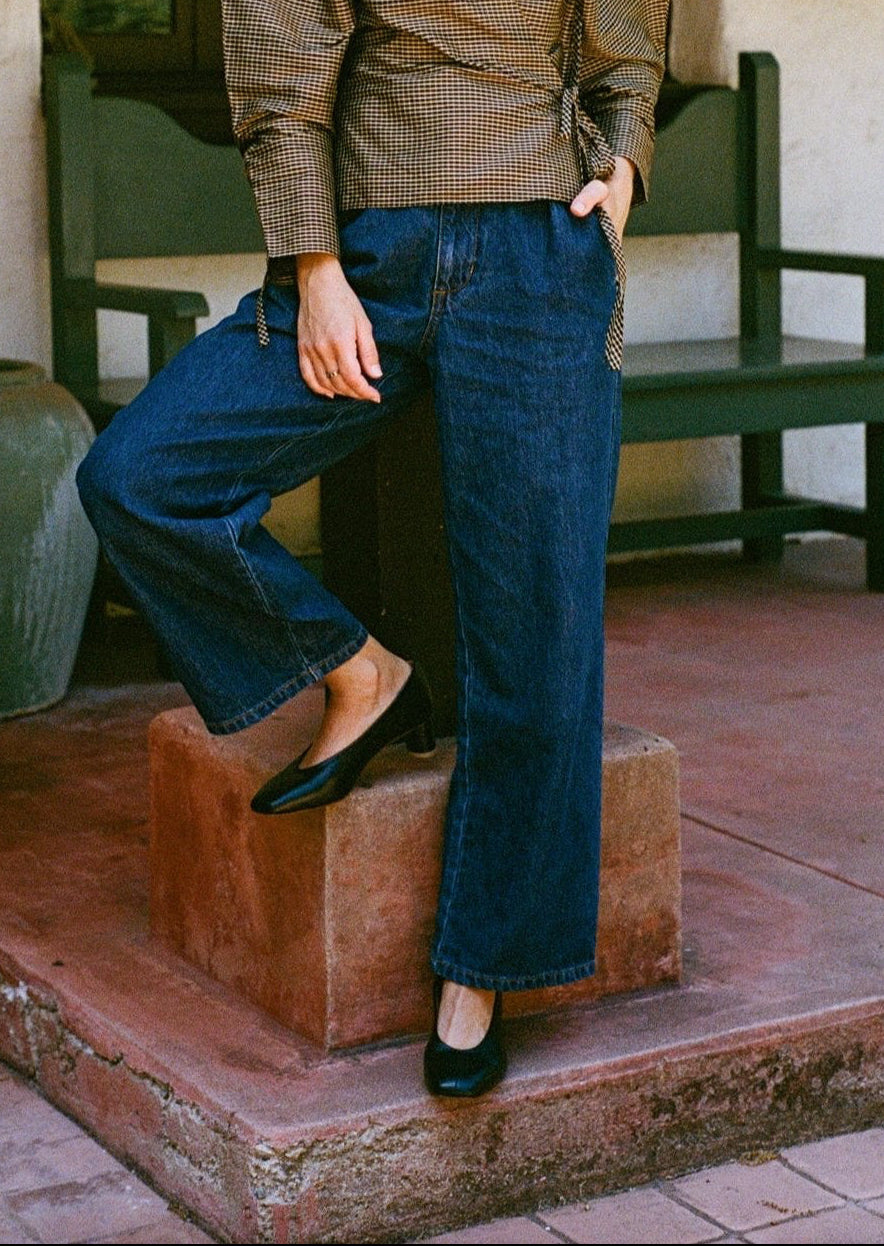 Model wears black leather pump with sculptural oval heel and center seam.