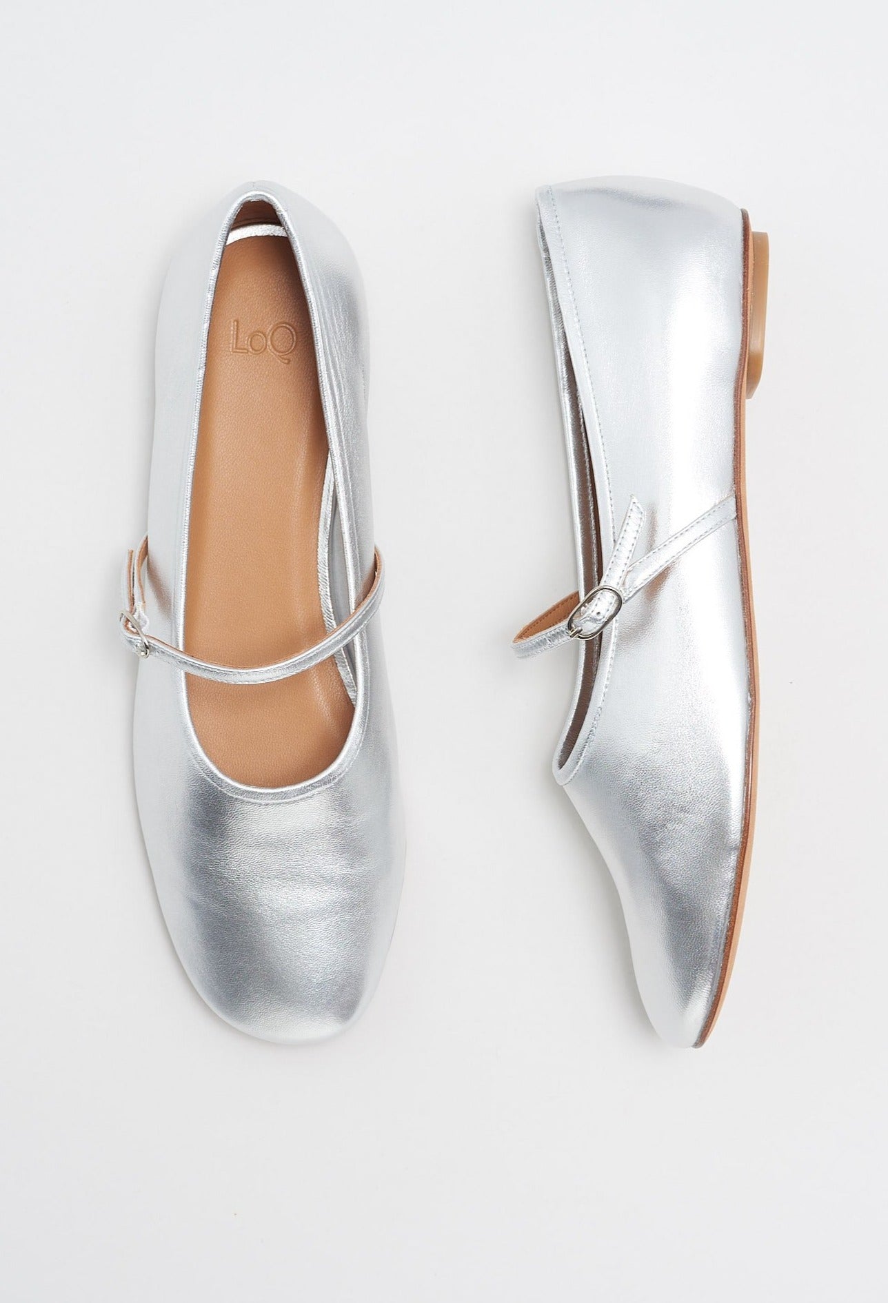 Metallic silver colored leather mary jane style flat shoe with strap and buckle closure.