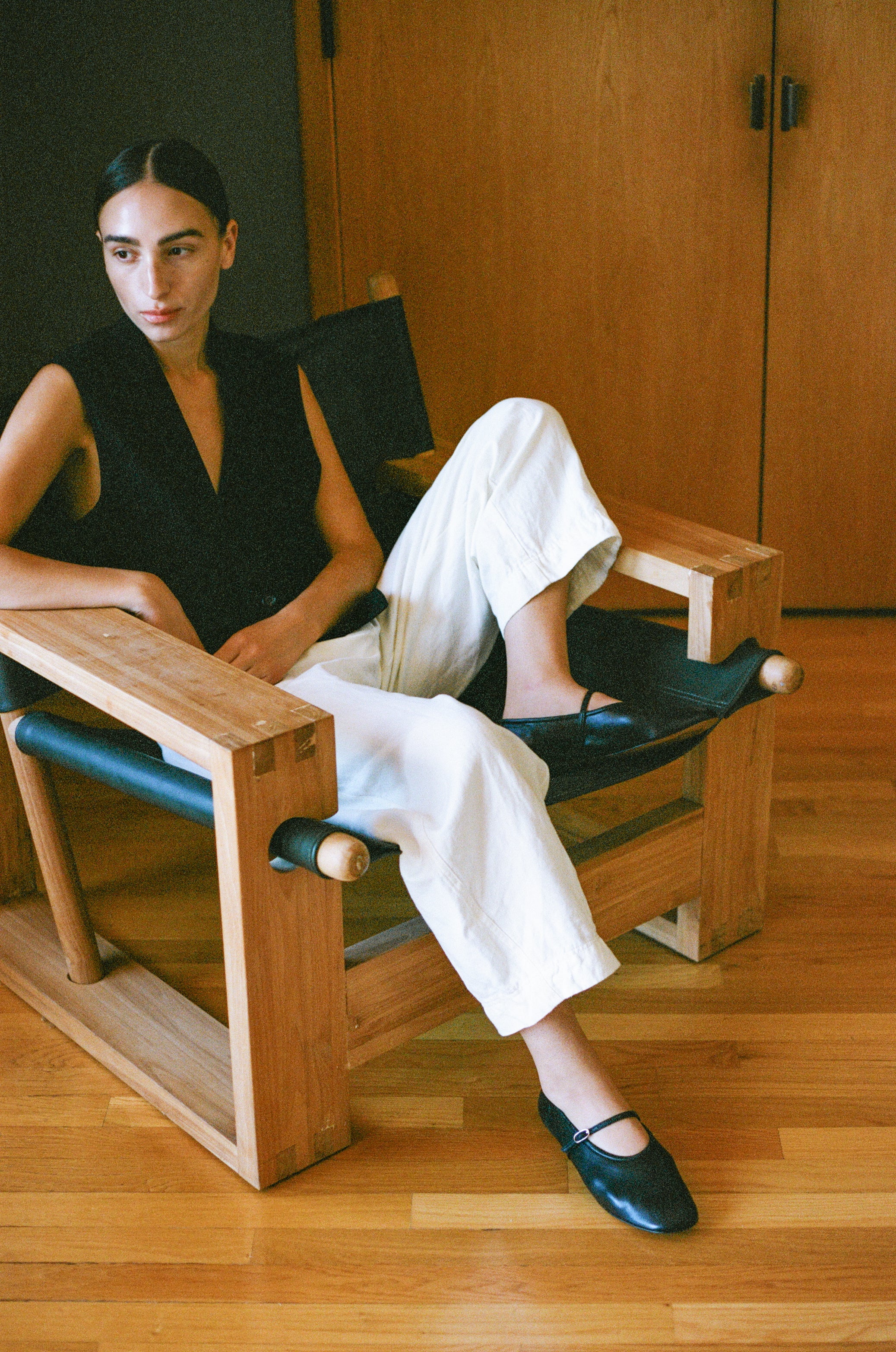 Model wears black leather mary jane style flat shoe with strap and buckle closure.