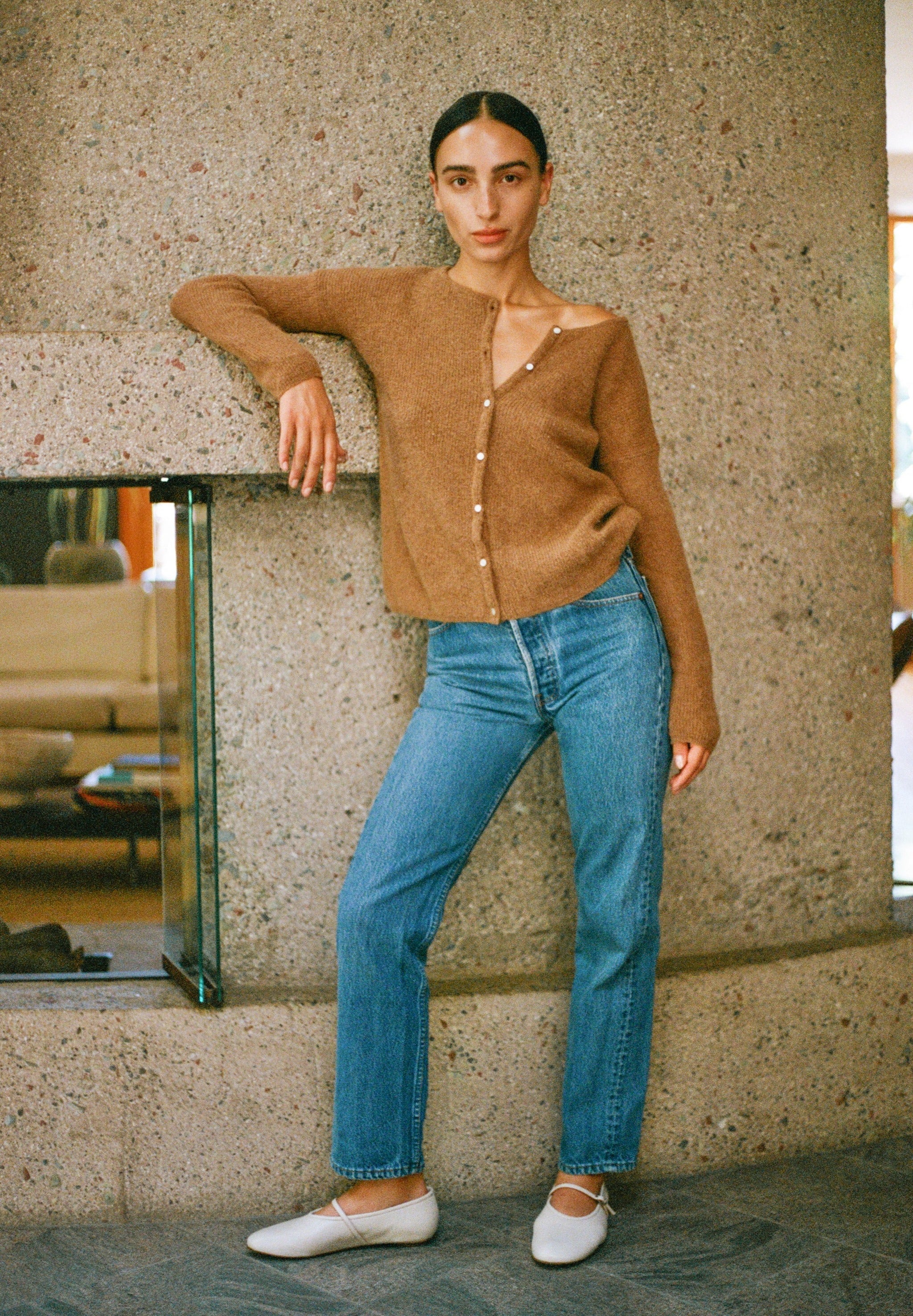 Model wears off white colored leather mary jane style flat shoe with strap and buckle closure.