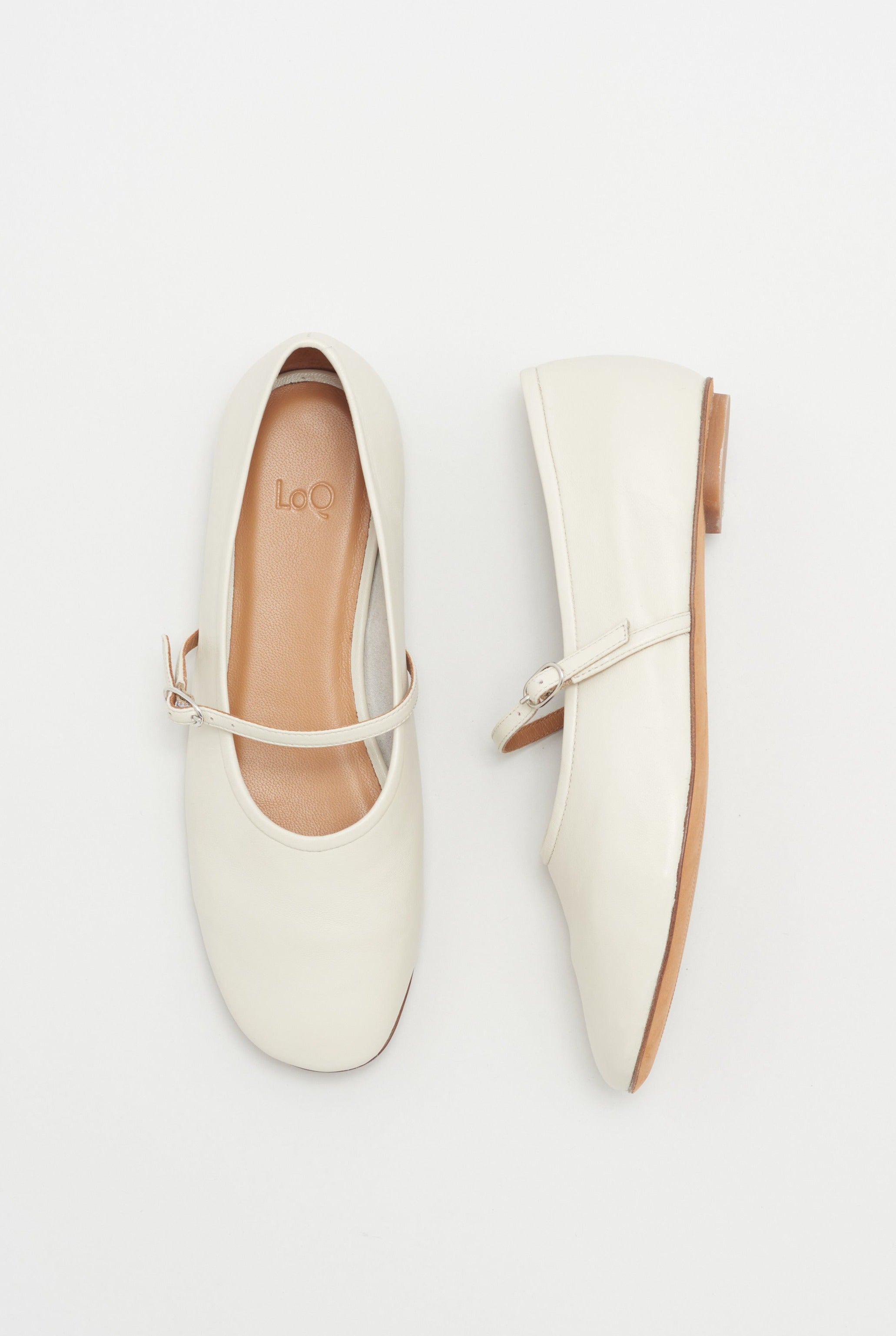 Off white colored leather mary jane style flat shoe with strap and buckle closure.