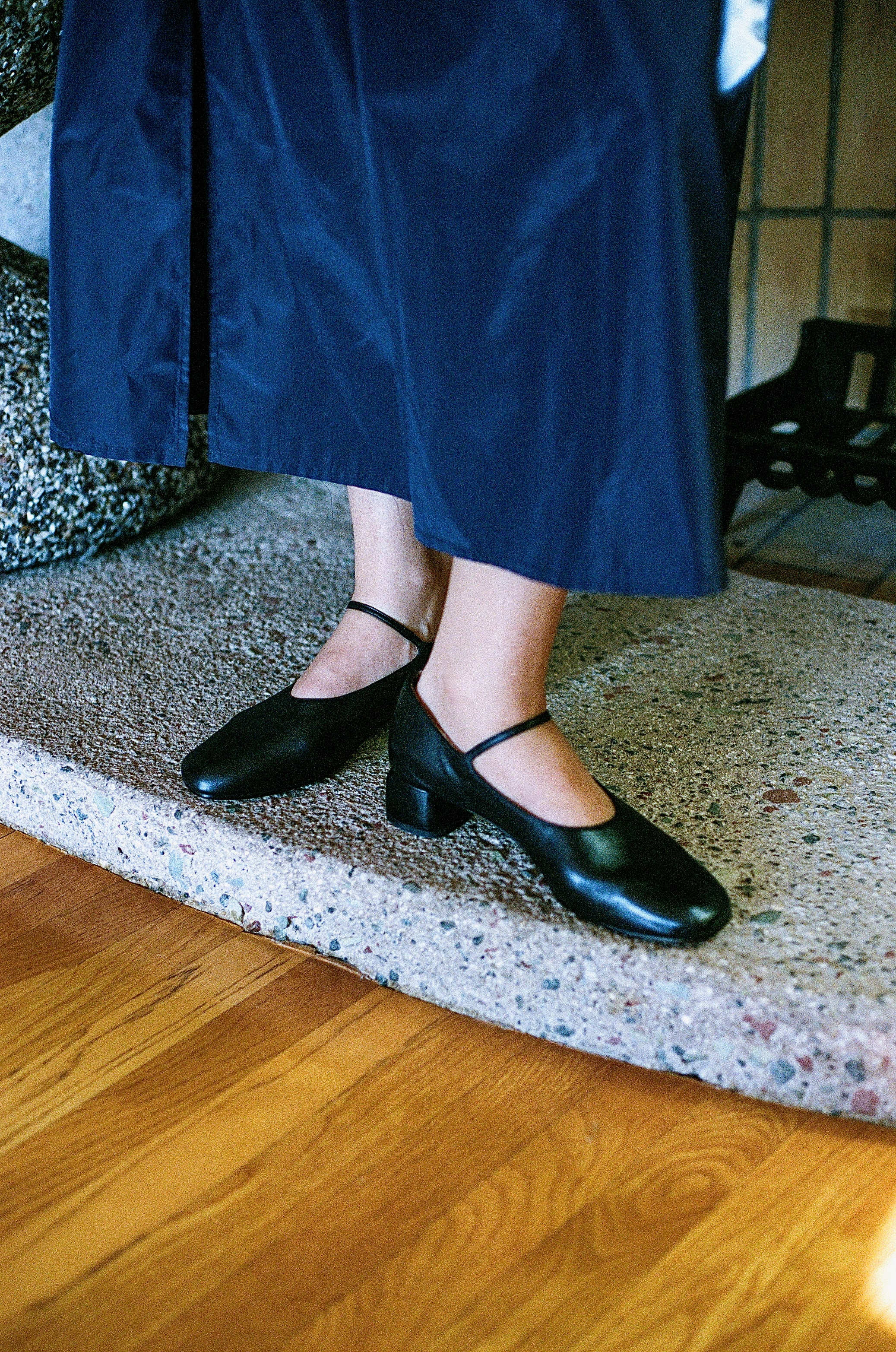 Model wears modern Mary Jane featuring a classic silver buckle with an updated round heel in black leather. Round toe and 1" covered heel.