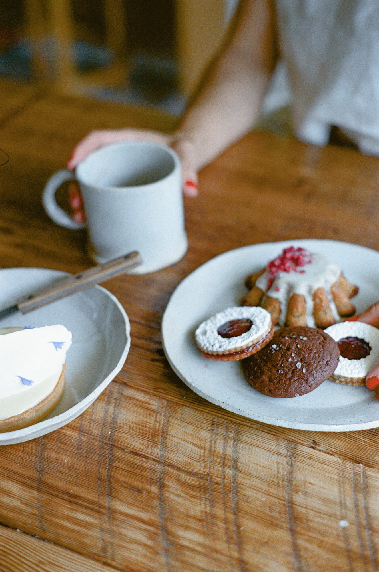 Model poses with white ceramic plates with pastries and mug.
