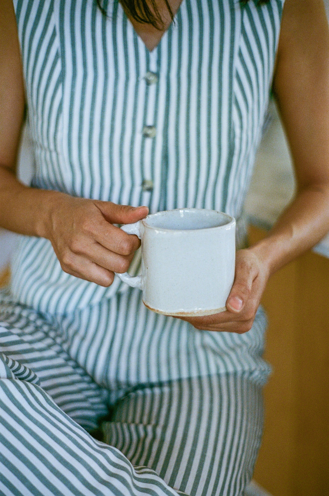 Model holds white ceramic mug.