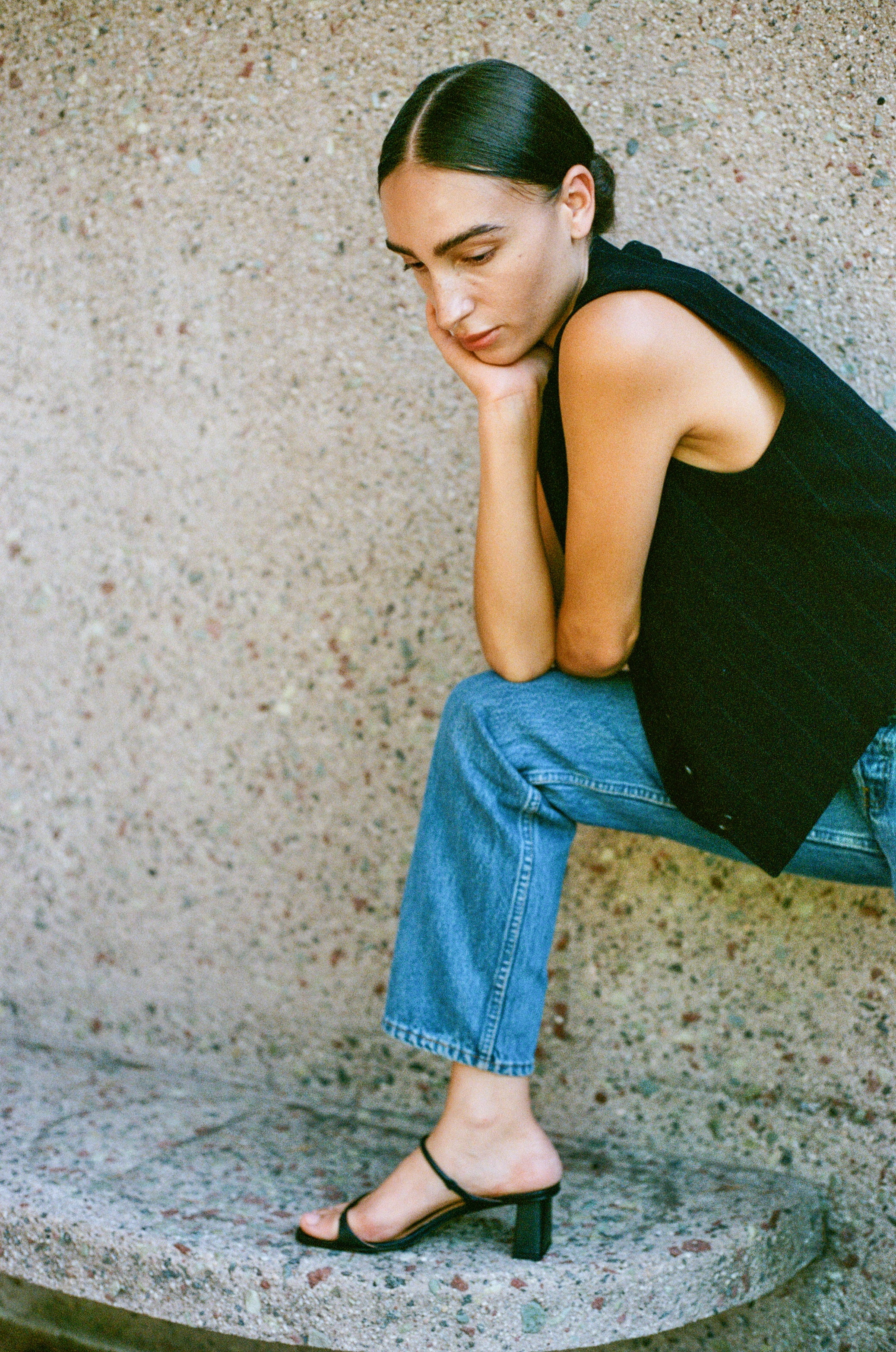 Model wears black heeled leather sandal featuring two thin straps and square block heel.