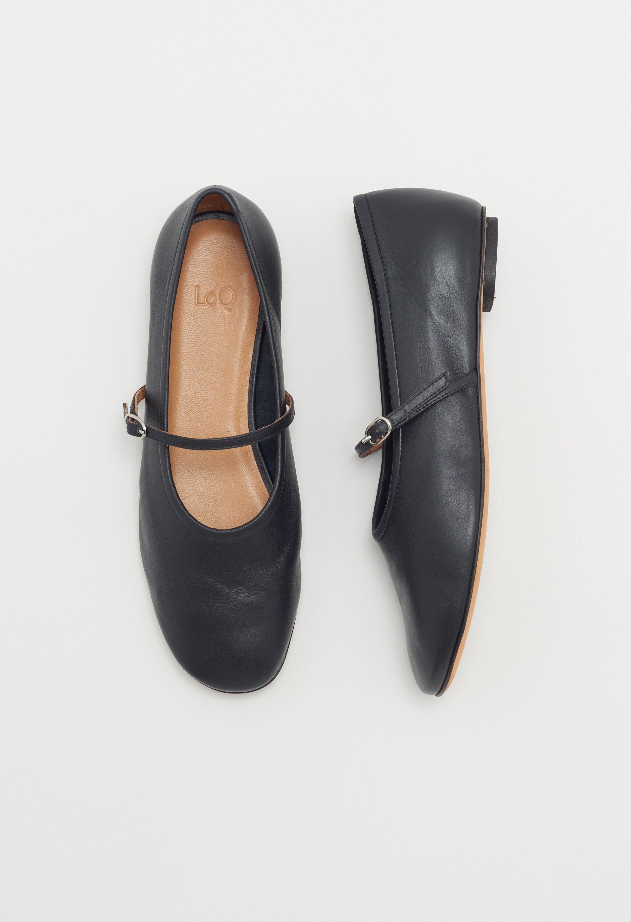 Black leather mary jane style flat shoe with strap and buckle closure.