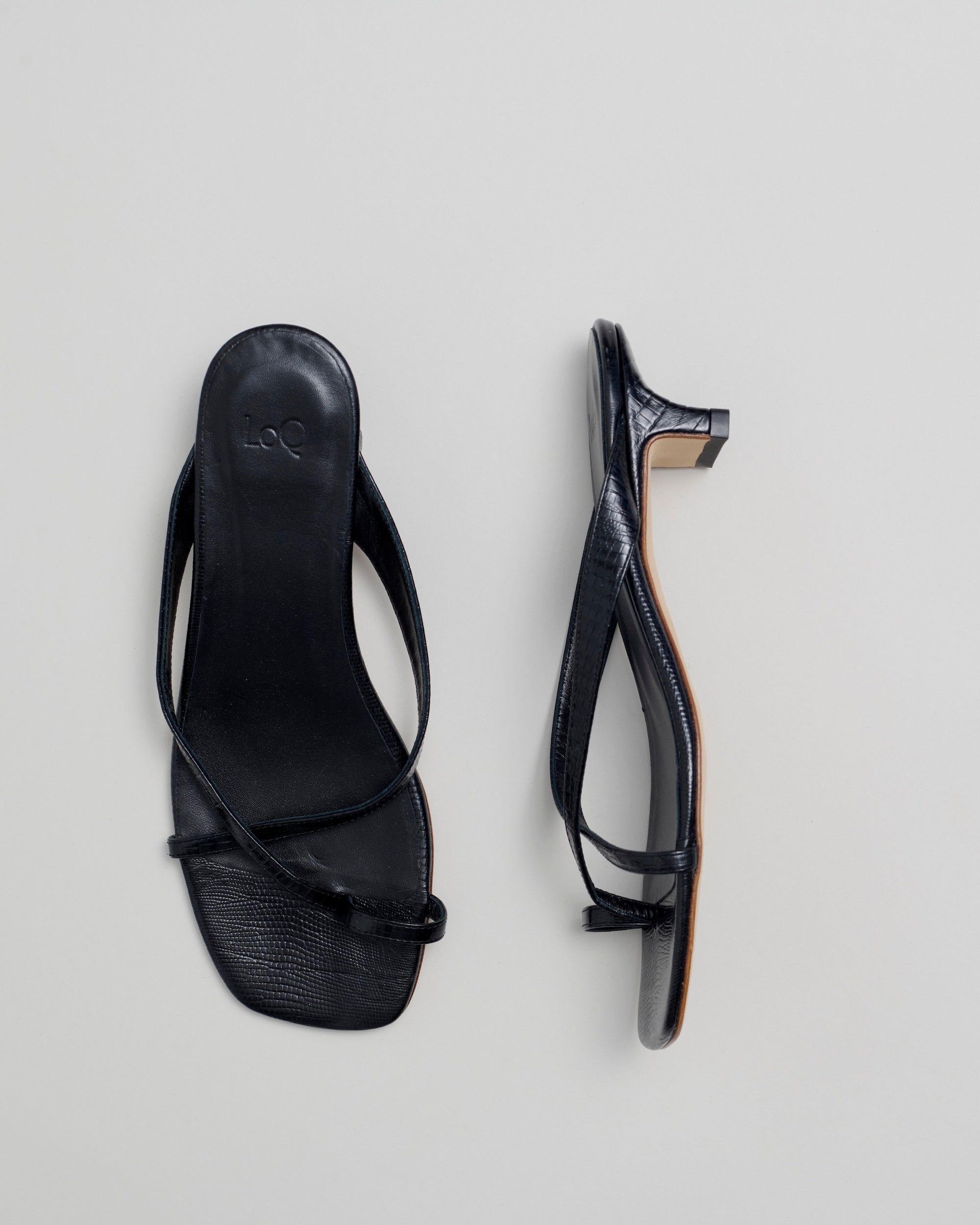 Black sandal with a strap on a light gray background