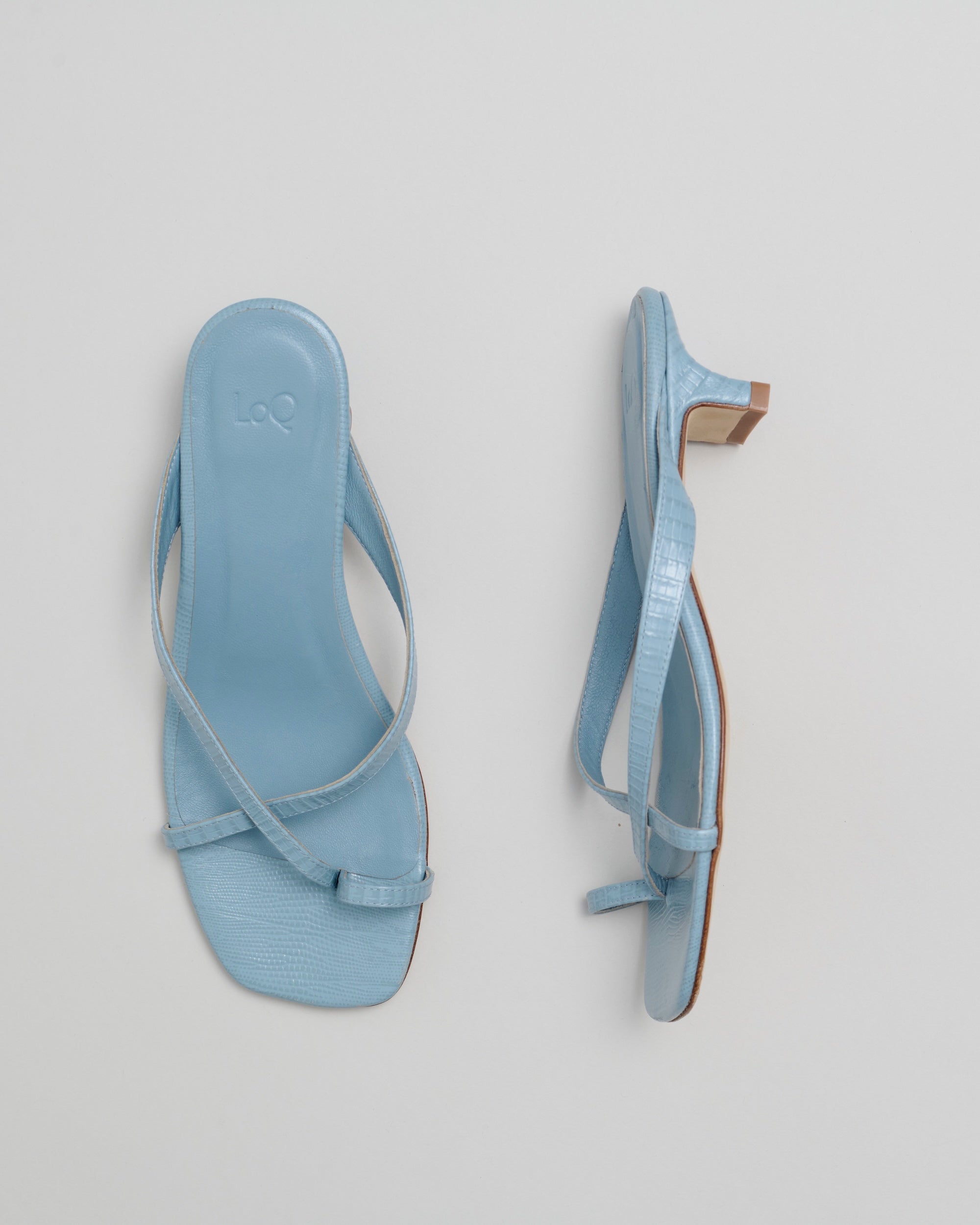 Pair of light blue sandals on a gray background