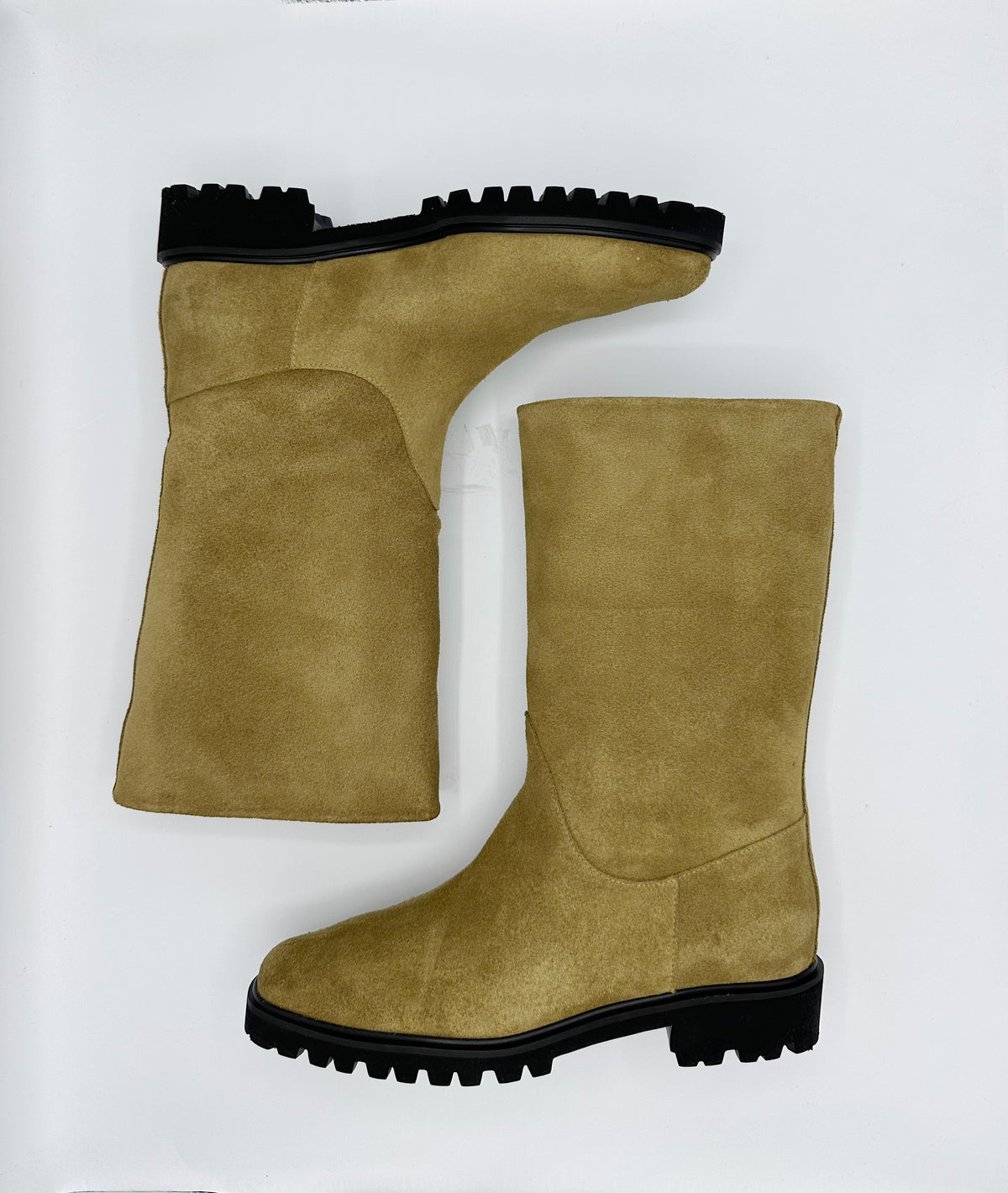A pair of mid-calf suede boots in a cumin color with black lug soles.
