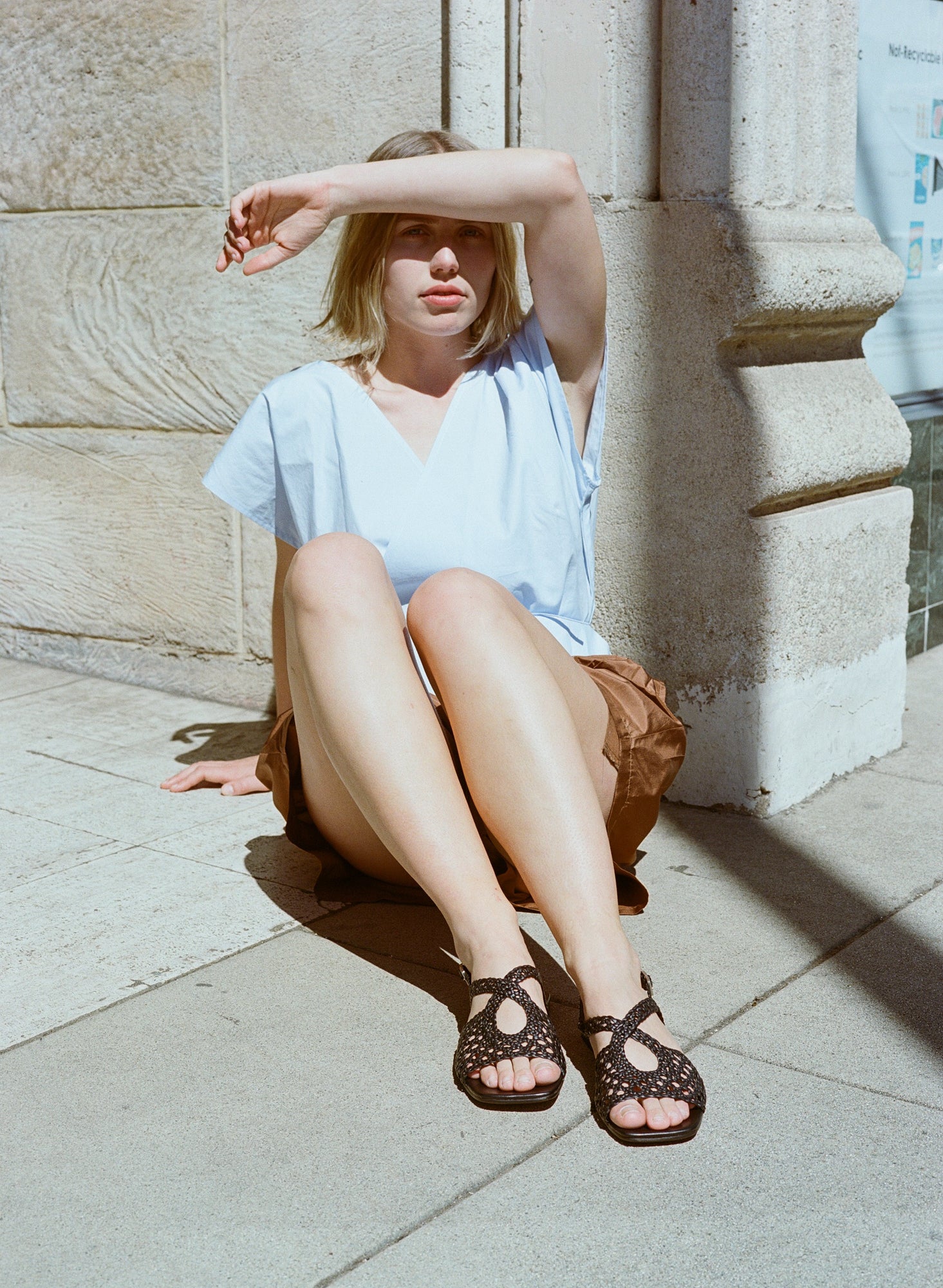 Model wears flat black leather sandals with lattice woven upper and slingback buckle.