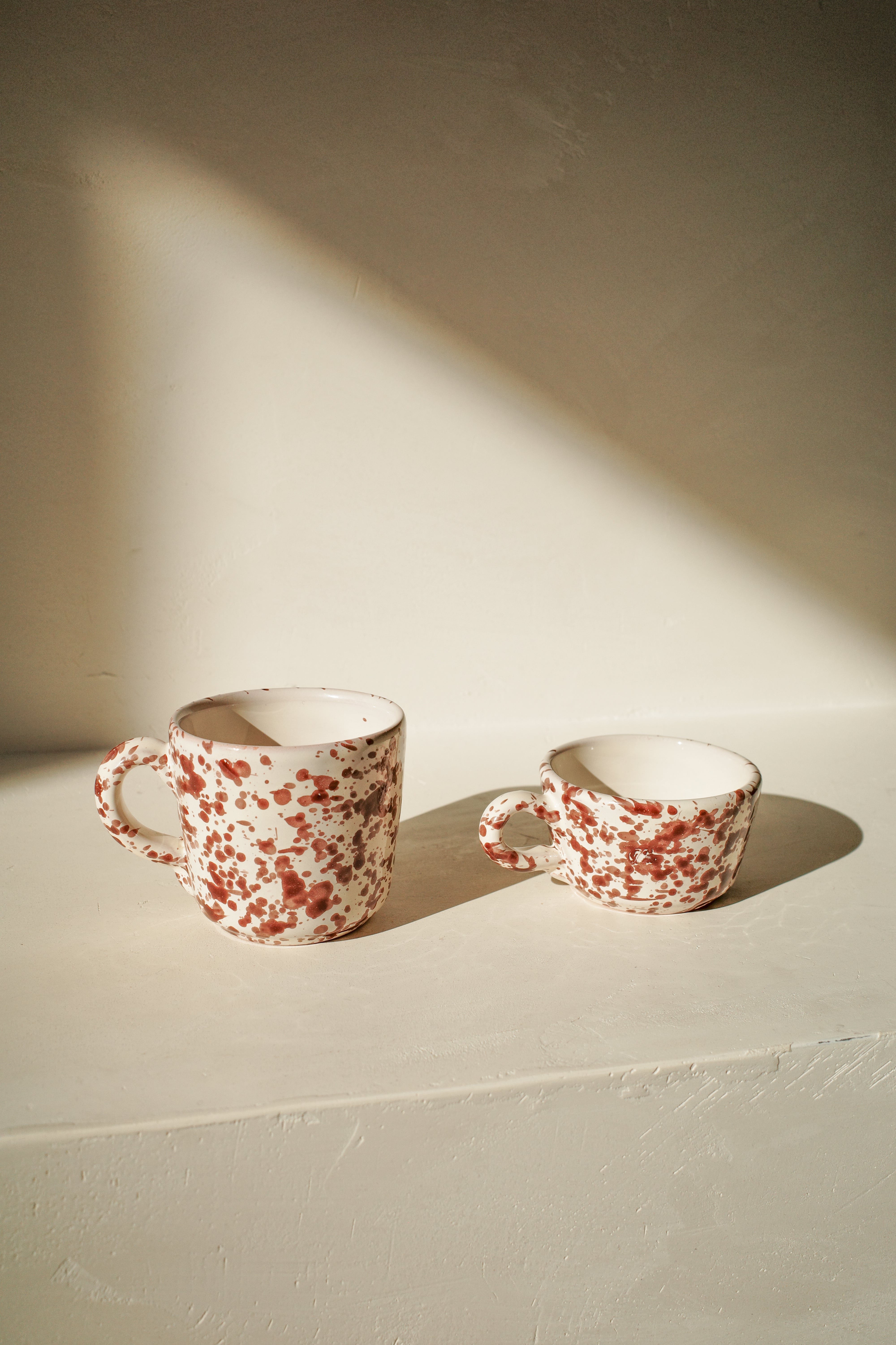 Ceramic coffee and espresso cup with white glaze and brown splatter pattern.