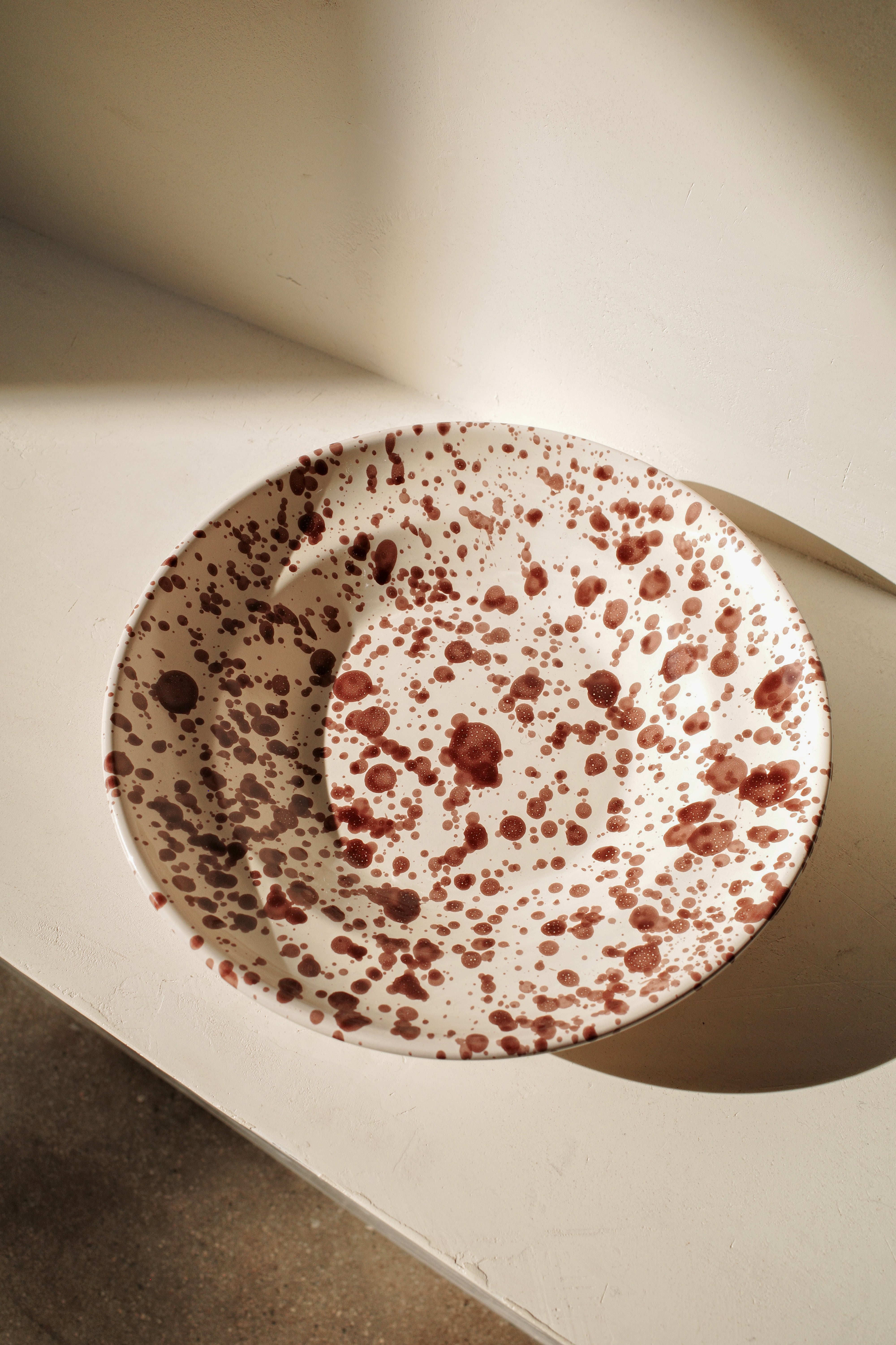 Ceramic deep plate with white glaze and dark brown paint splatter.