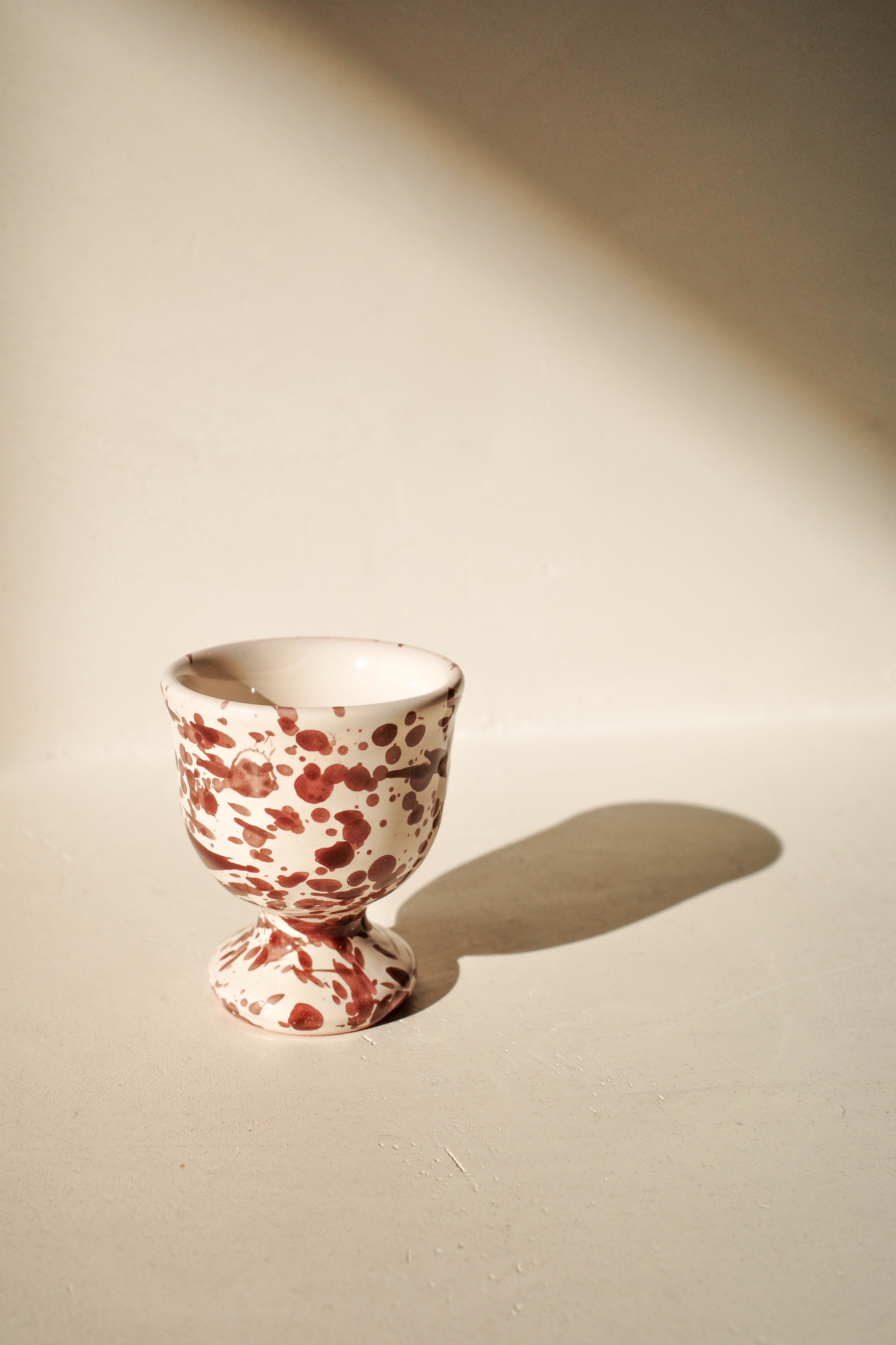 Ceramic egg cup with white and brown splatter pattern.