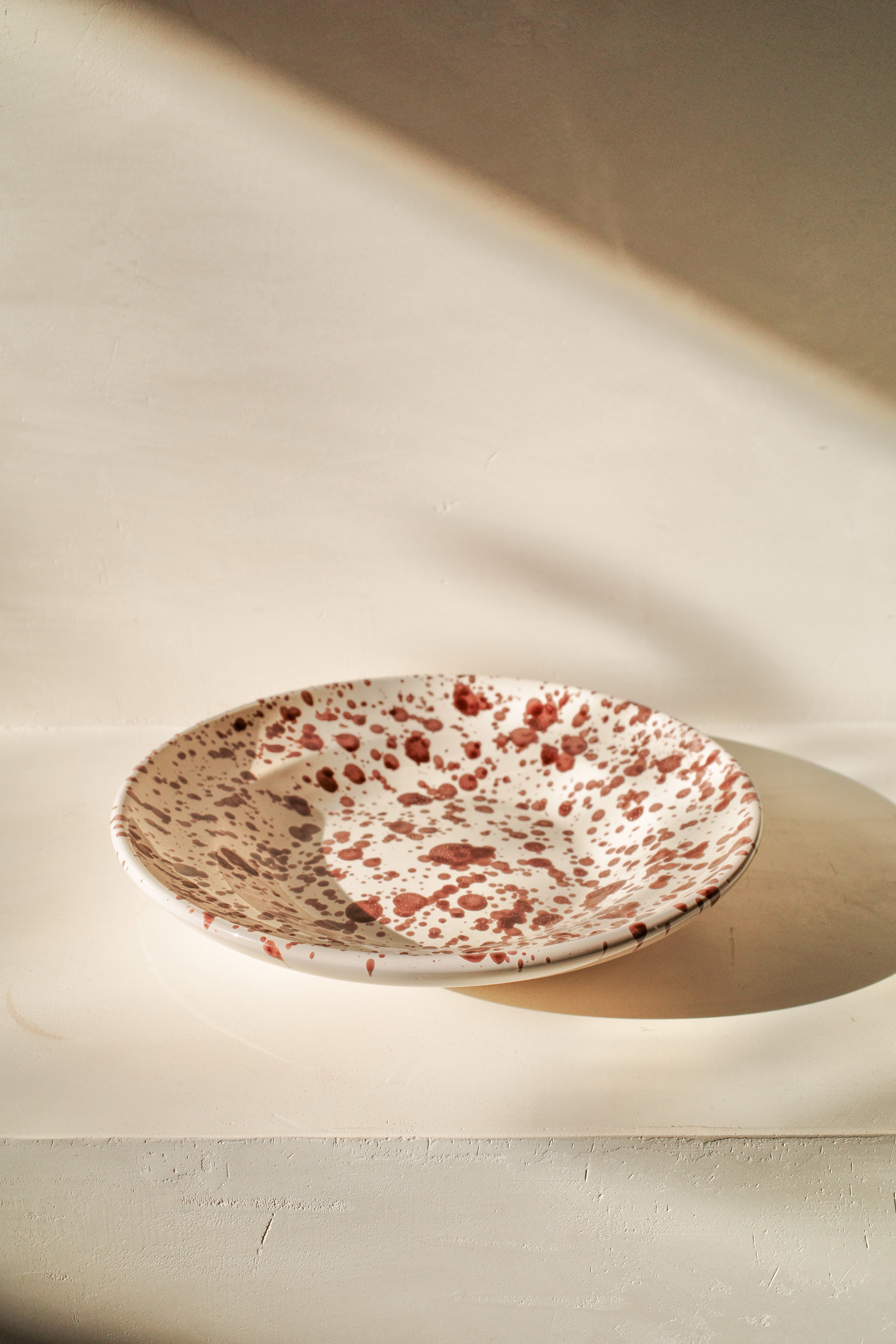 Ceramic deep plate with white glaze and dark brown paint splatter.