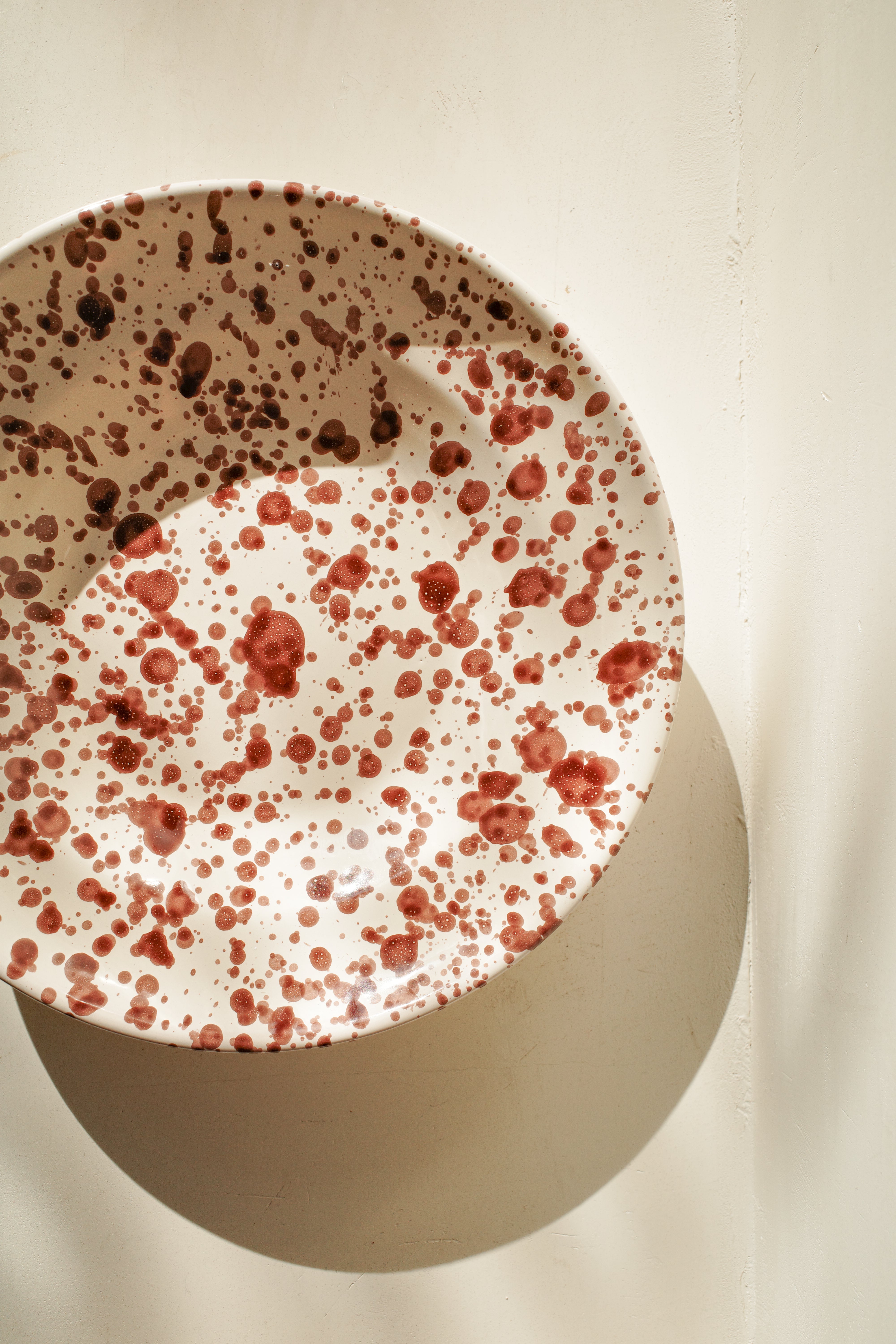 Ceramic deep plate with white glaze and dark brown paint splatter.