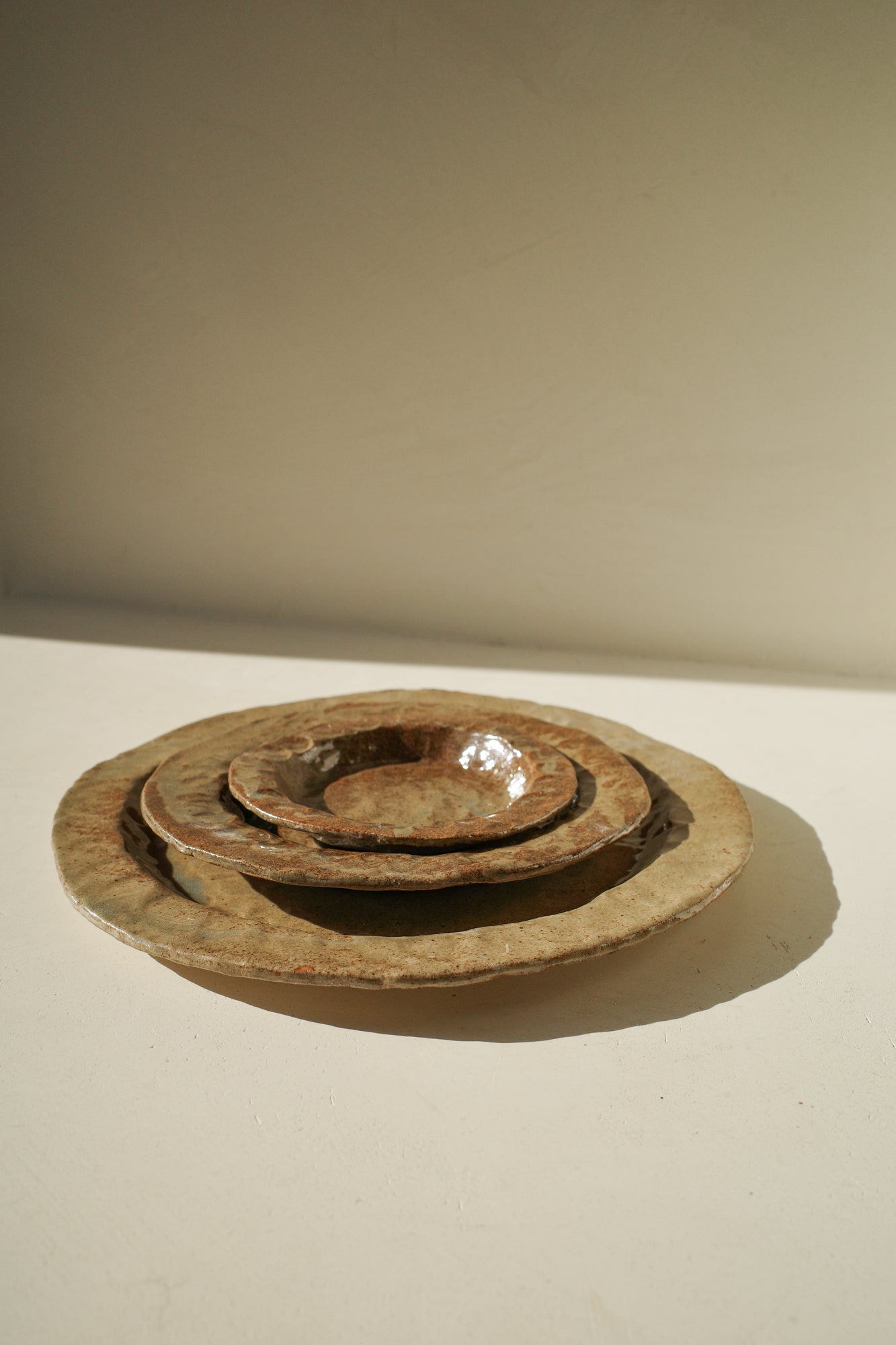 Handmade ceramic plates in varying sizes and brown glaze.