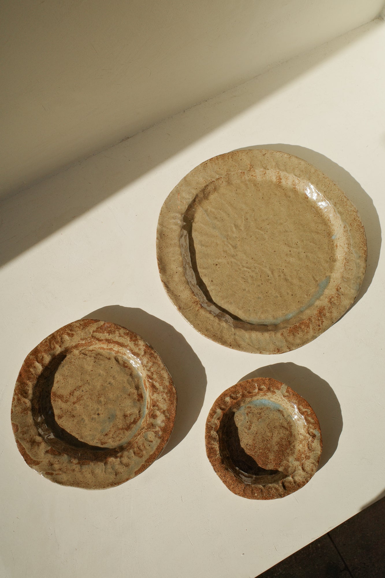 Handmade ceramic plates in varying sizes and brown glaze.