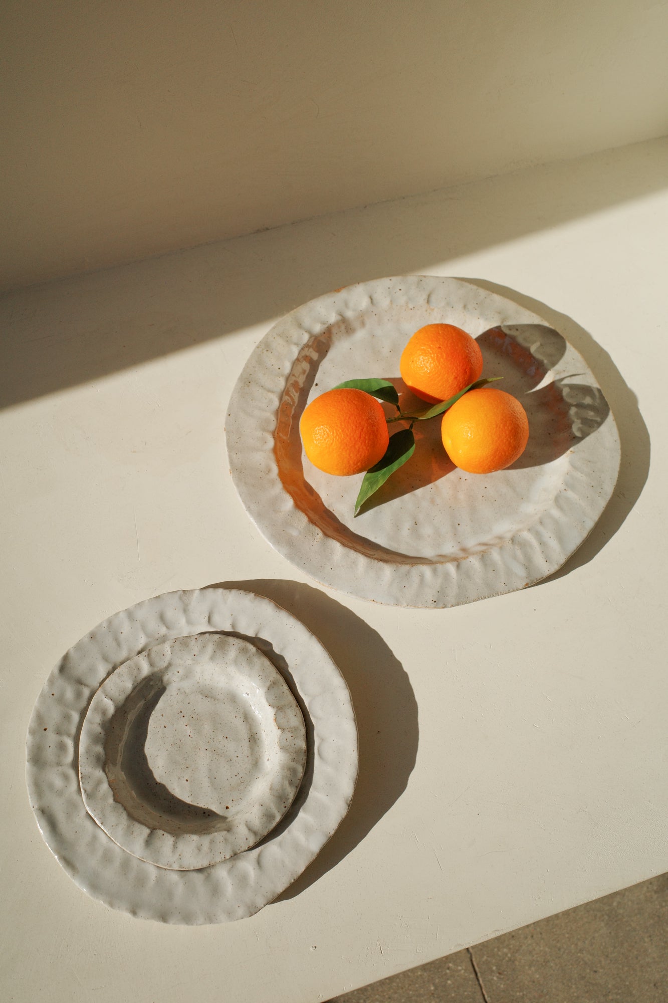 Handmade ceramic plates with white glaze in three sizes.