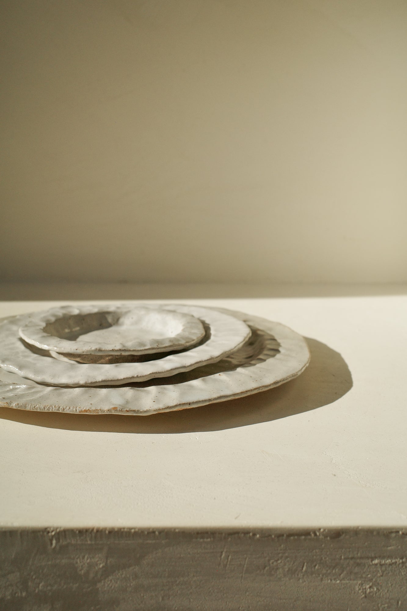 Handmade ceramic plates with white glaze in three sizes.