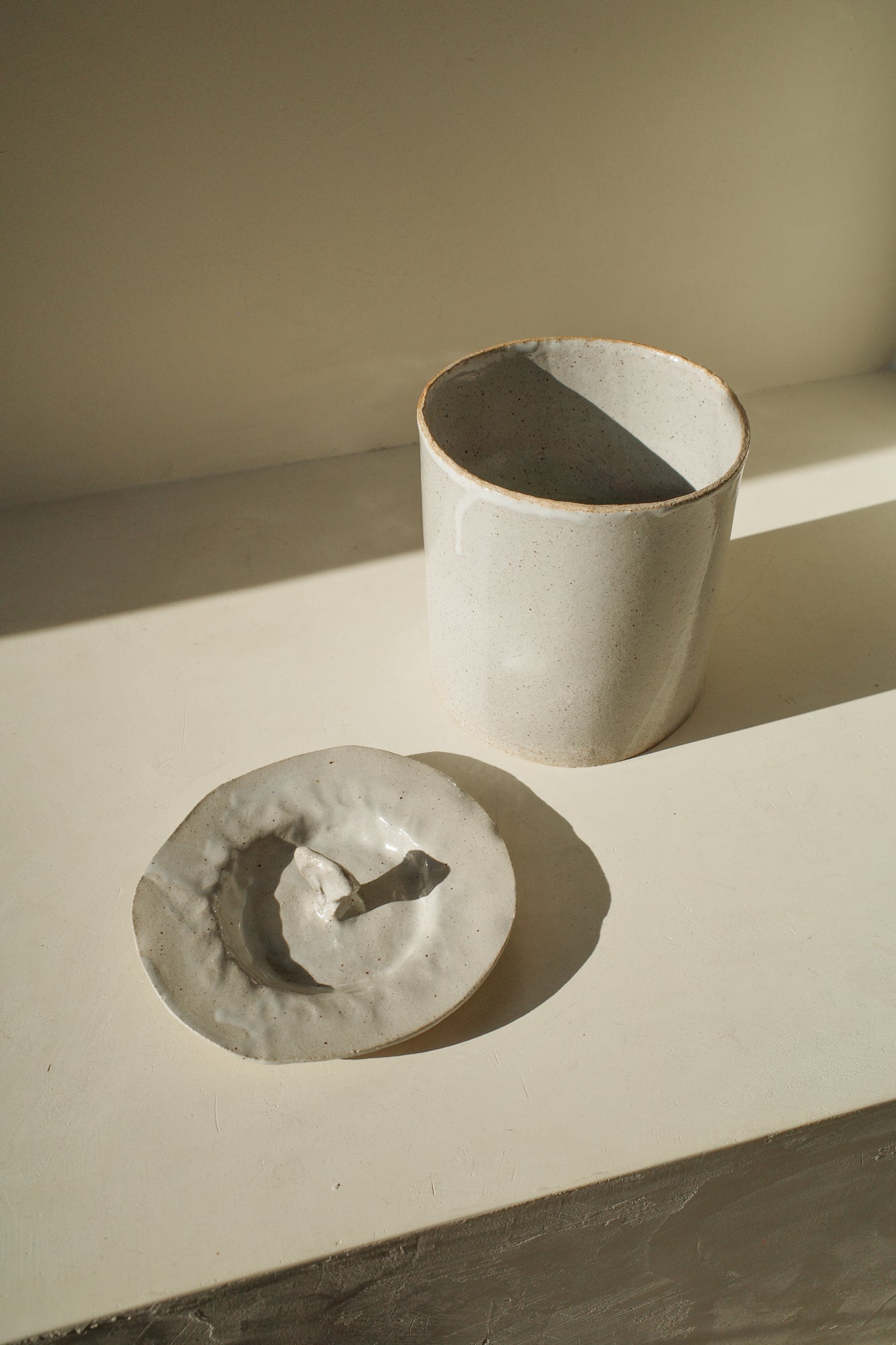 Large handbuilt ceramic jar with white glaze and removable lid.