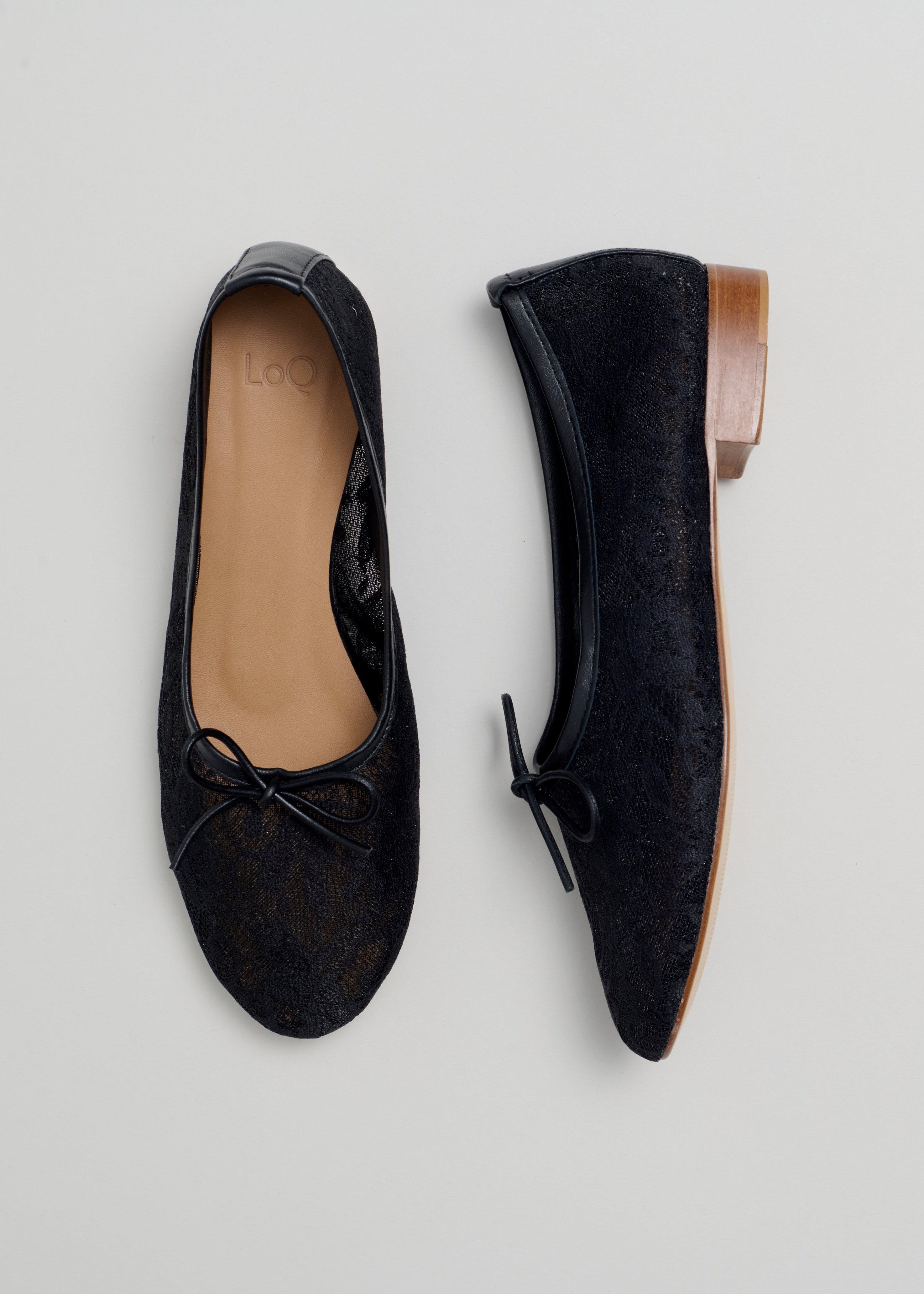 Pair of black lace ballet flats on a light gray background