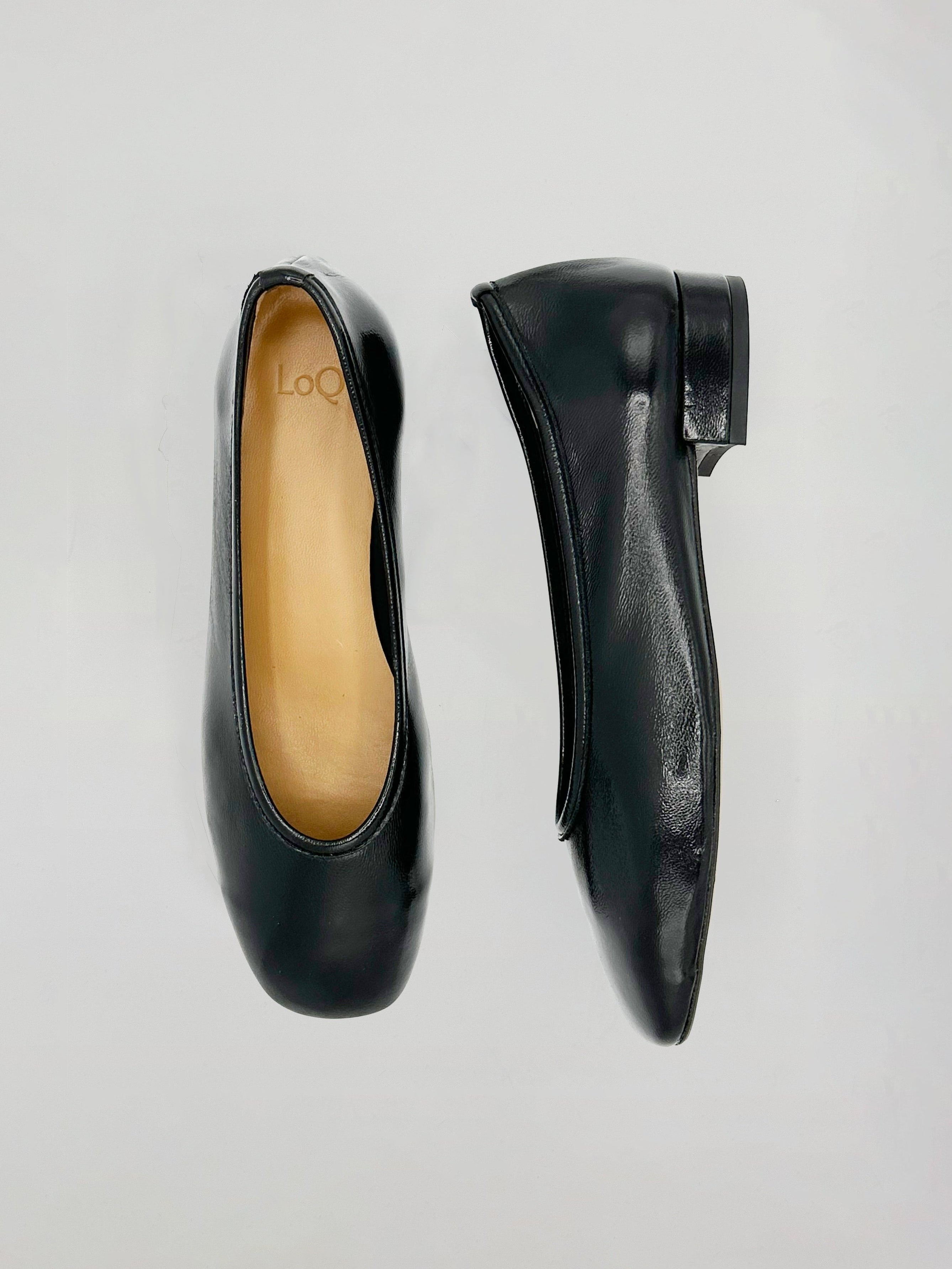 A pair of black leather ballet flats shown from top and side views on a light gray background. The interior insole features the brand name 'Loc'.