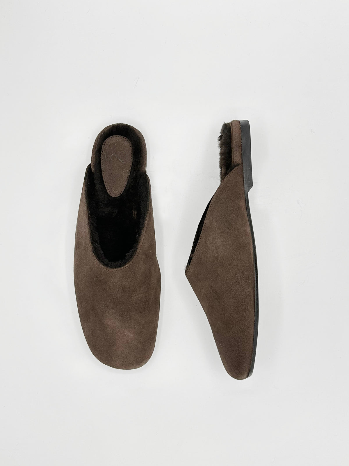 A pair of dark brown suede slip-on slippers with black fur lining.