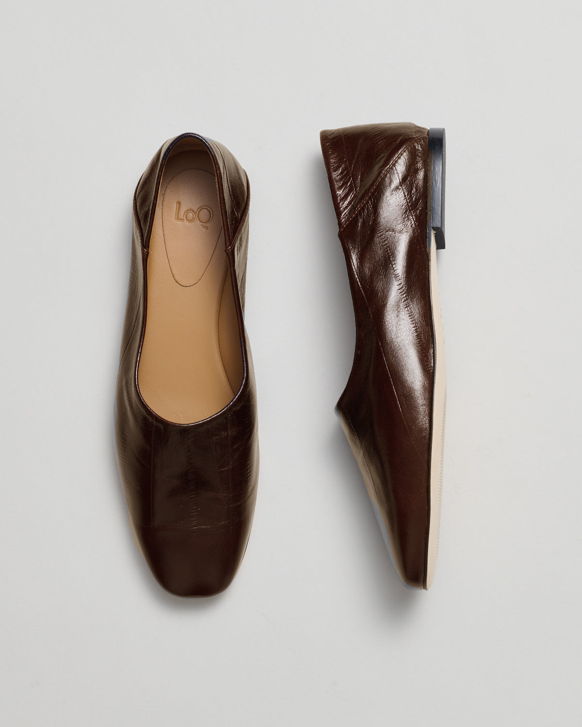A pair of dark brown leather ballet flats shown from the top and side views on a light gray background.