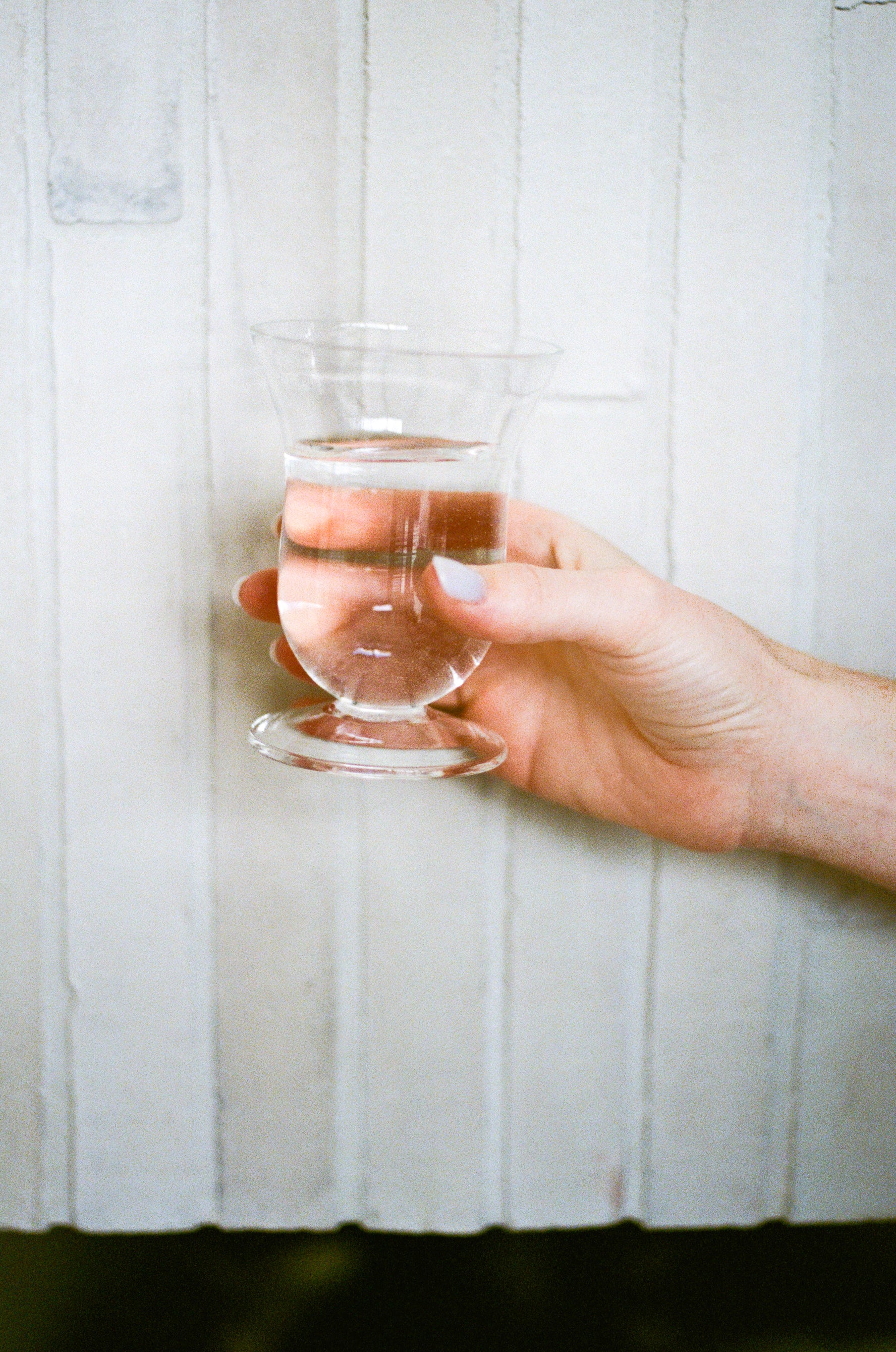 Model holds unique stemware for drinking - clear curvy water glass