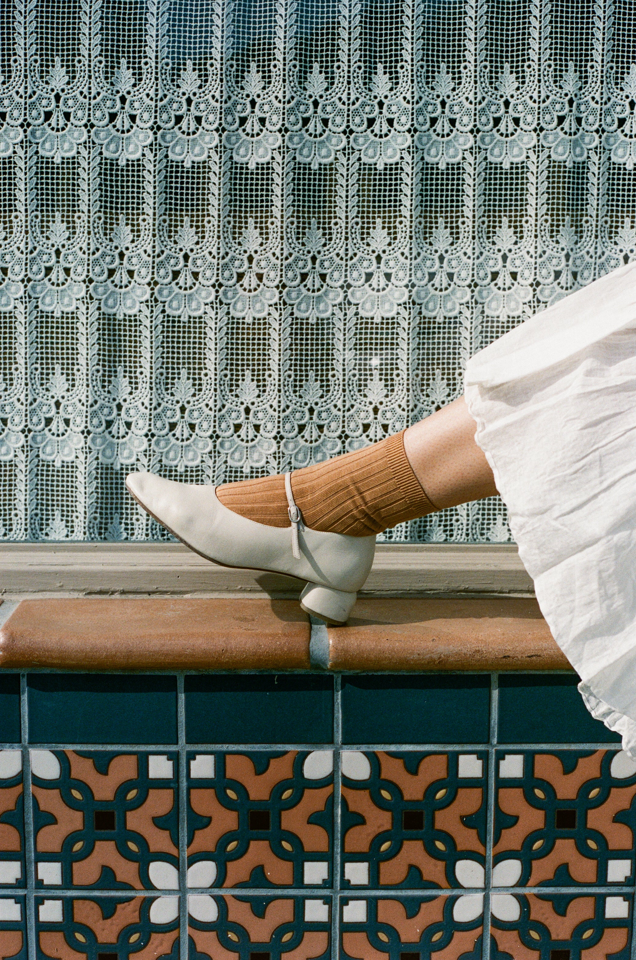 Model wears terracotta colored socks with white mary jane.