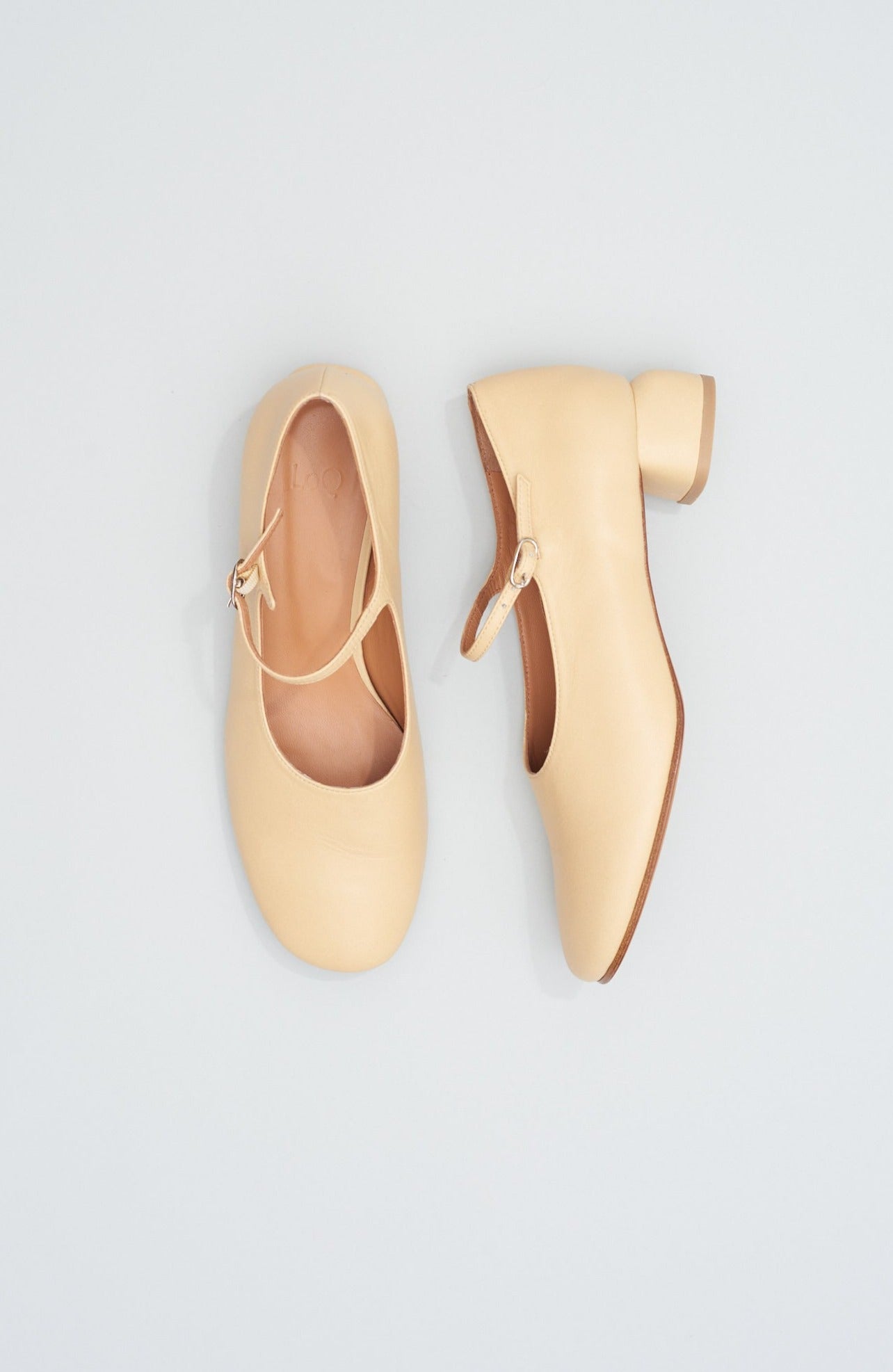 Modern Mary Jane featuring a classic silver buckle with an updated round heel in biscuit beige leather. Round toe and 1" covered heel.