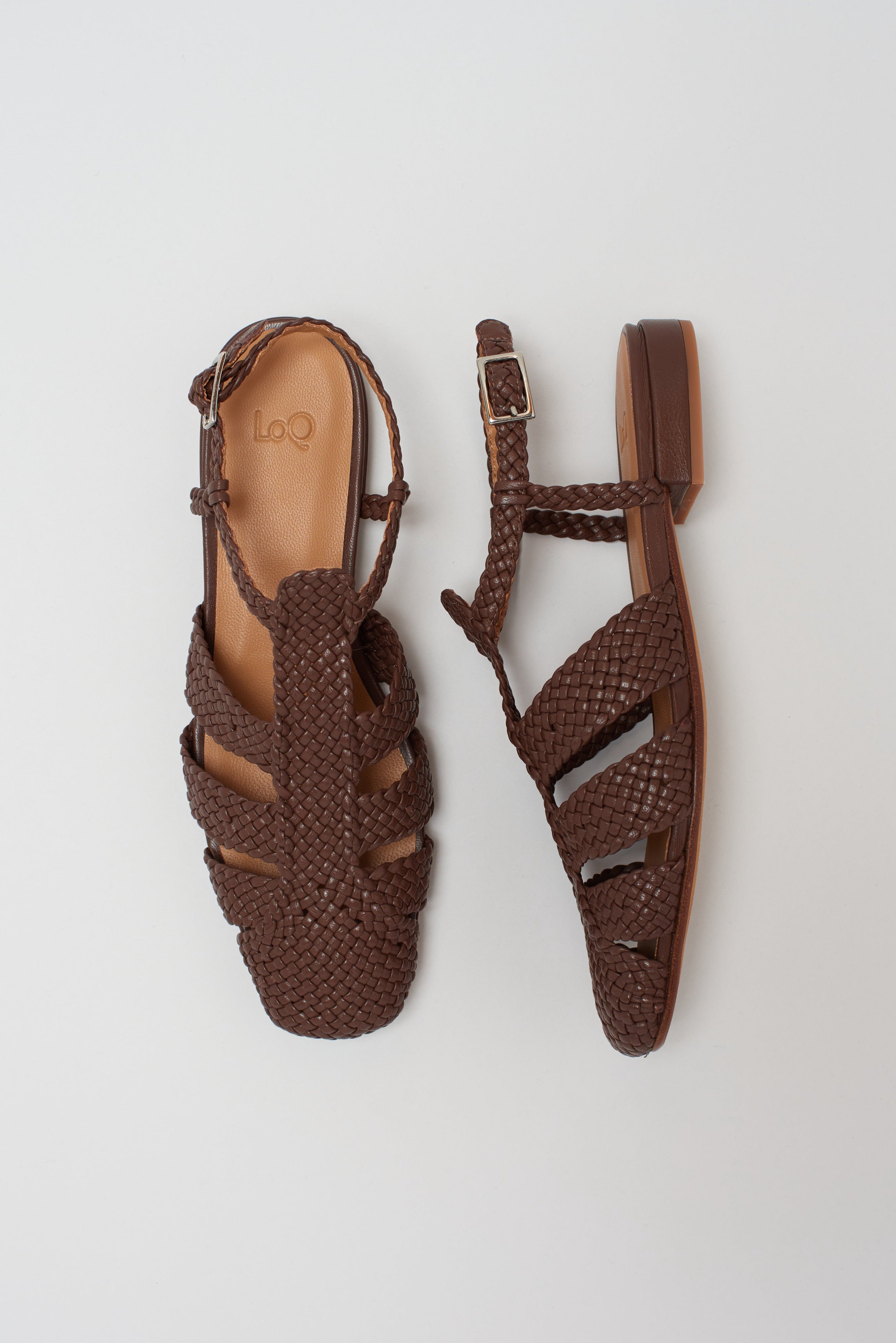 Brown leather fisherman-style sandals featuring straps made of woven leather across the foot and a strap that buckles around the ankle