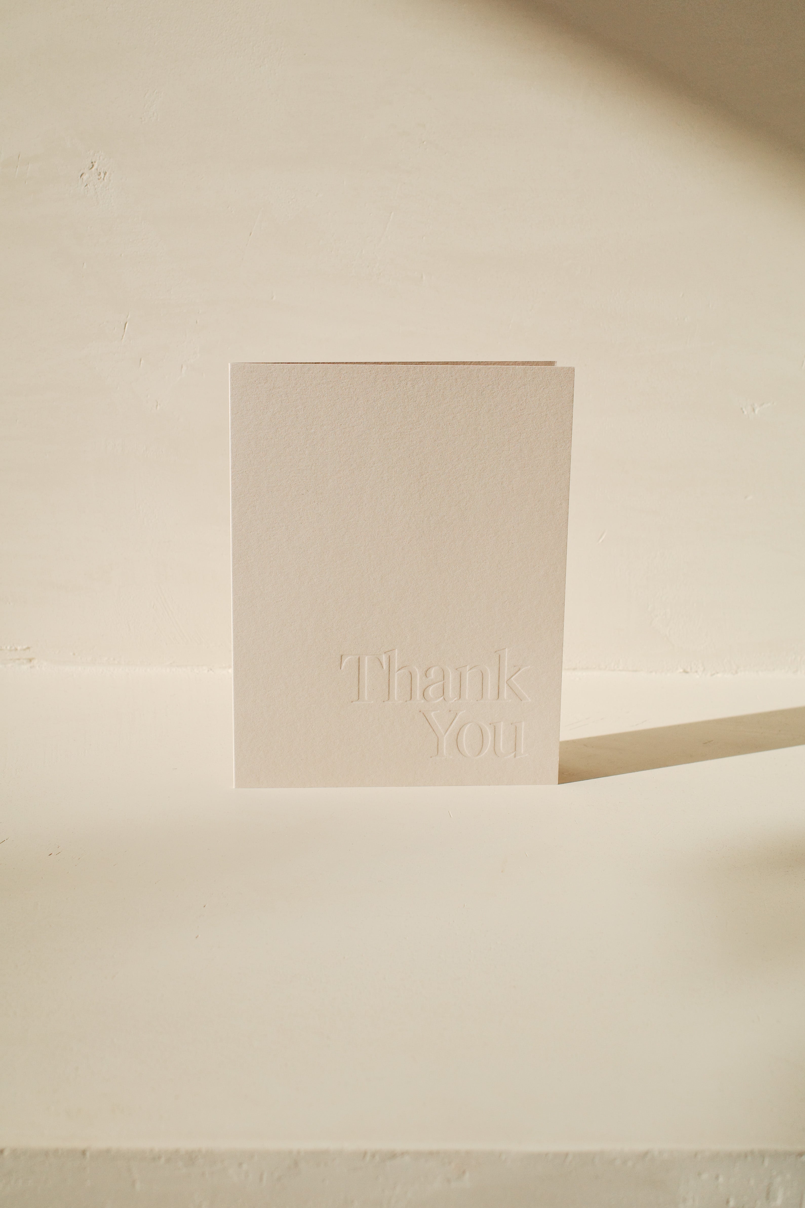 White greeting card with Thank You embossed on front.