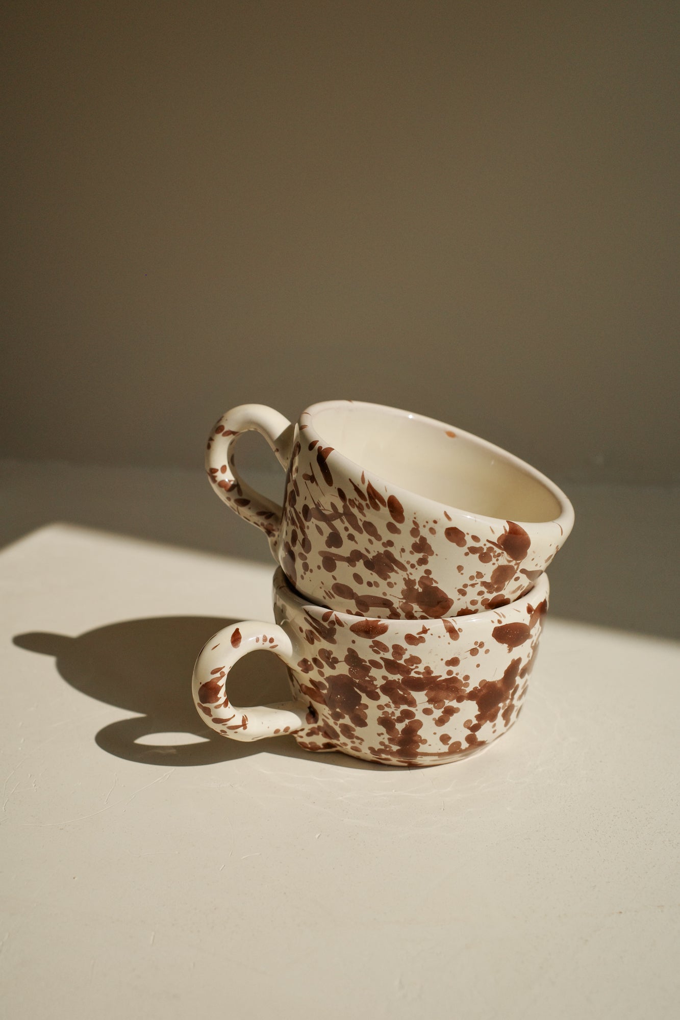 Ceramic espresso cups with white glaze and dark brown splatter pattern.