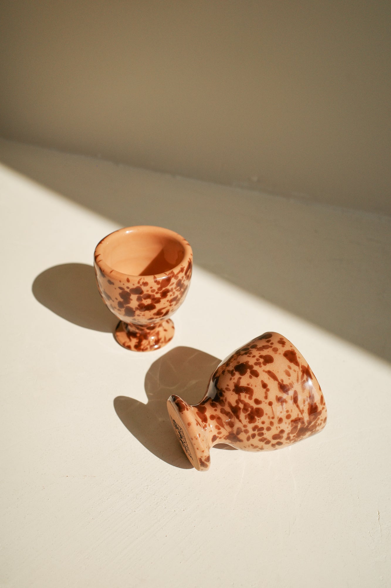 Ceramic egg cups with terracotta glaze and brown splatter pattern.