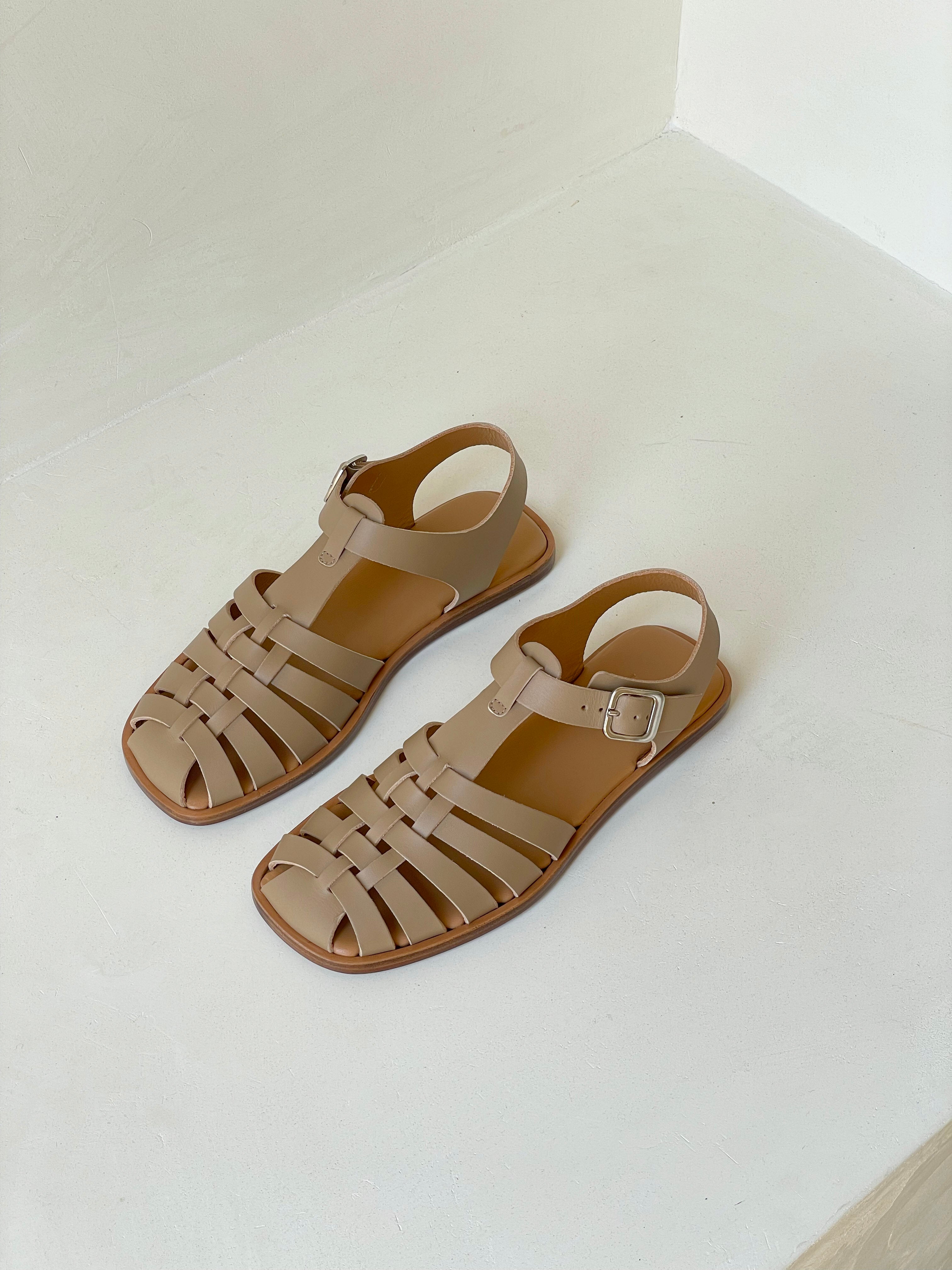 Fisherman sandal with a buckled closure and t-bar vamp in taupe leather. Vegetable-tanned leather upper and outsole.