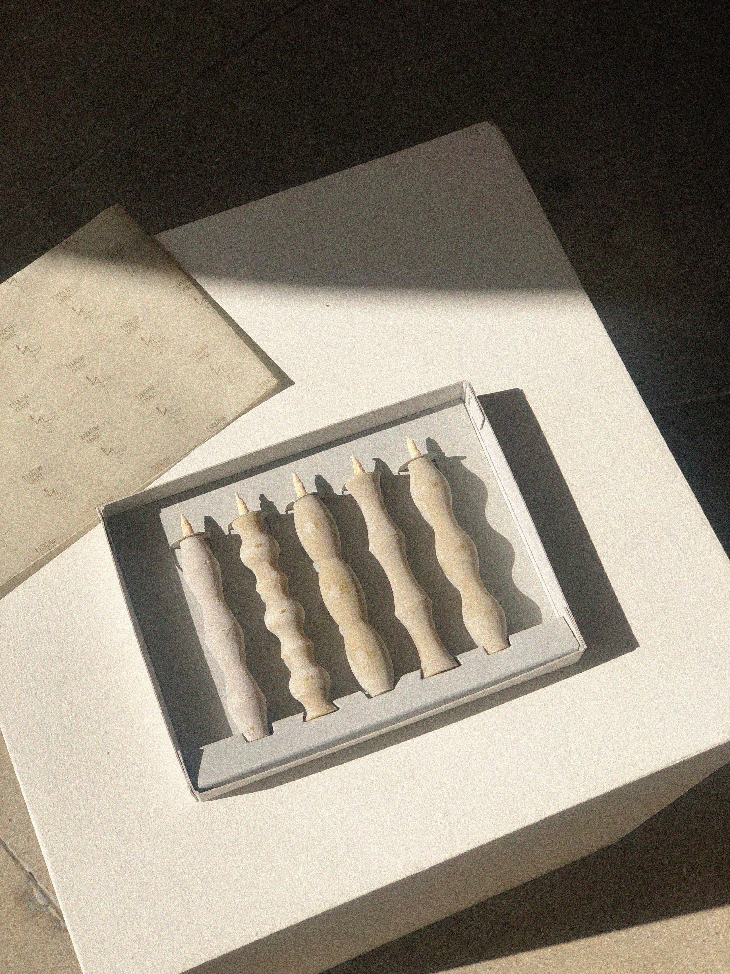 Set of five off-white candles, each one with a different wavy silhouette.