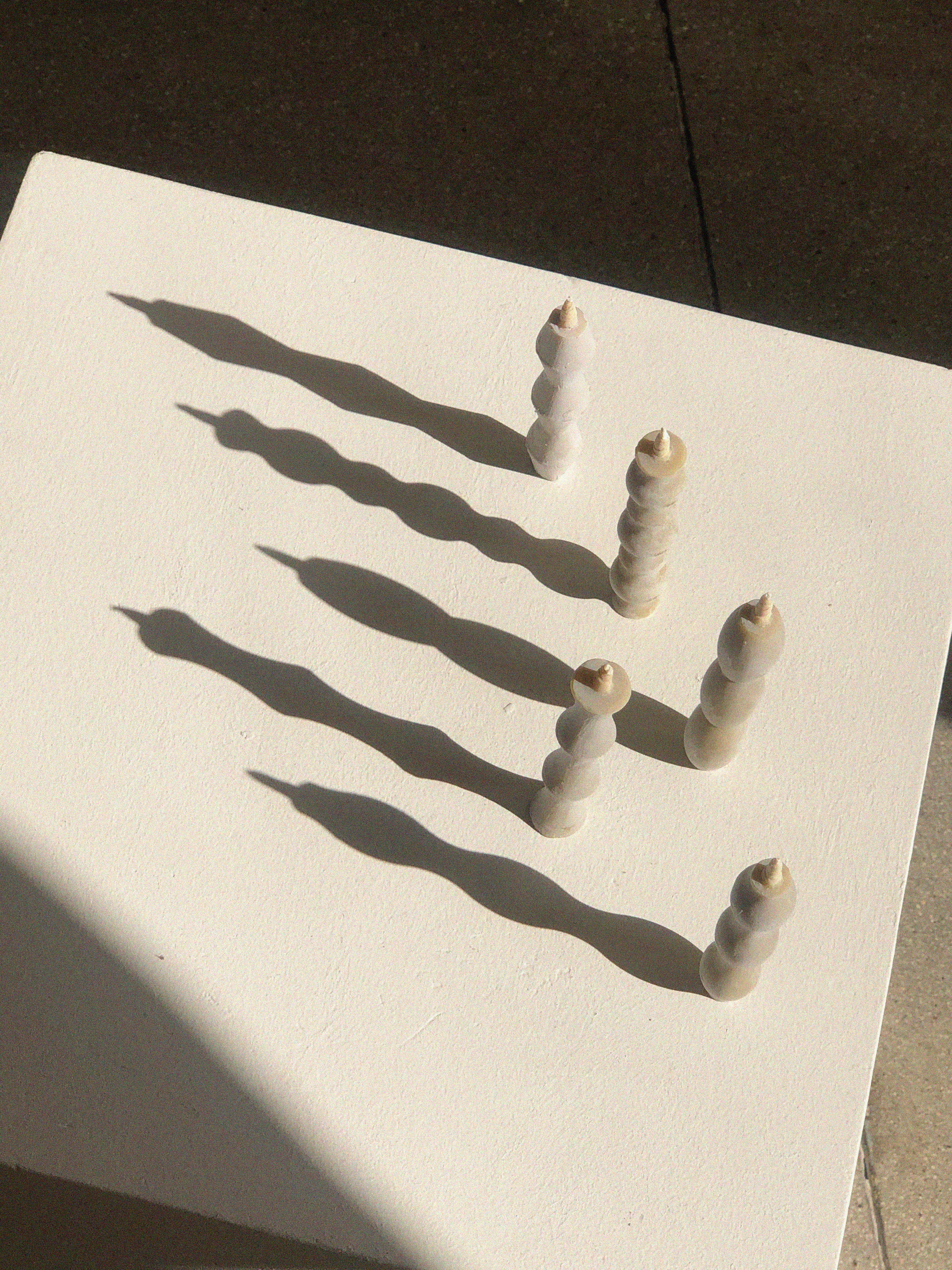 Set of five off-white candles, each one with a different wavy silhouette.