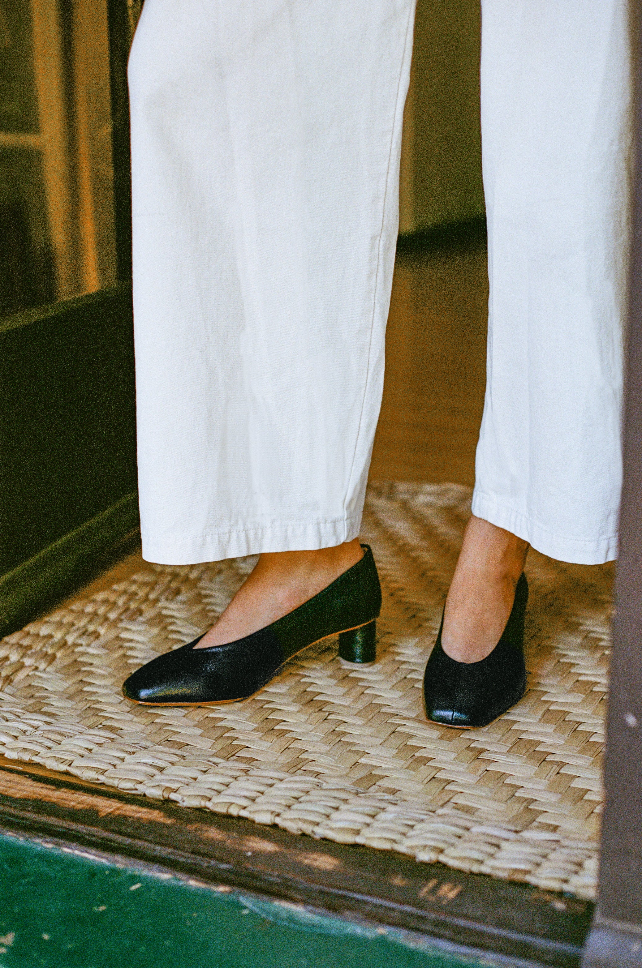 Model wears black leather pump with sculptural oval heel and center seam.